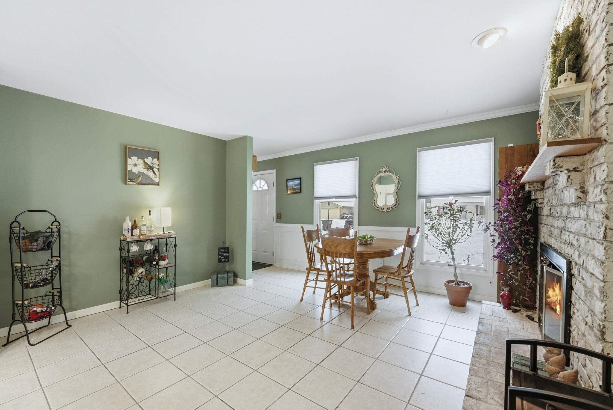 Dining area featuring a brick fireplace, tile patterned floors, and ornamental molding
