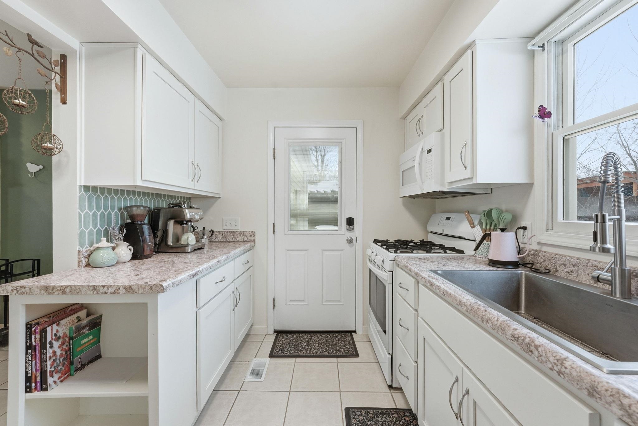Kitchen featuring white cabinets, white appliances, backsplash, light countertops, and light tile patterned floors