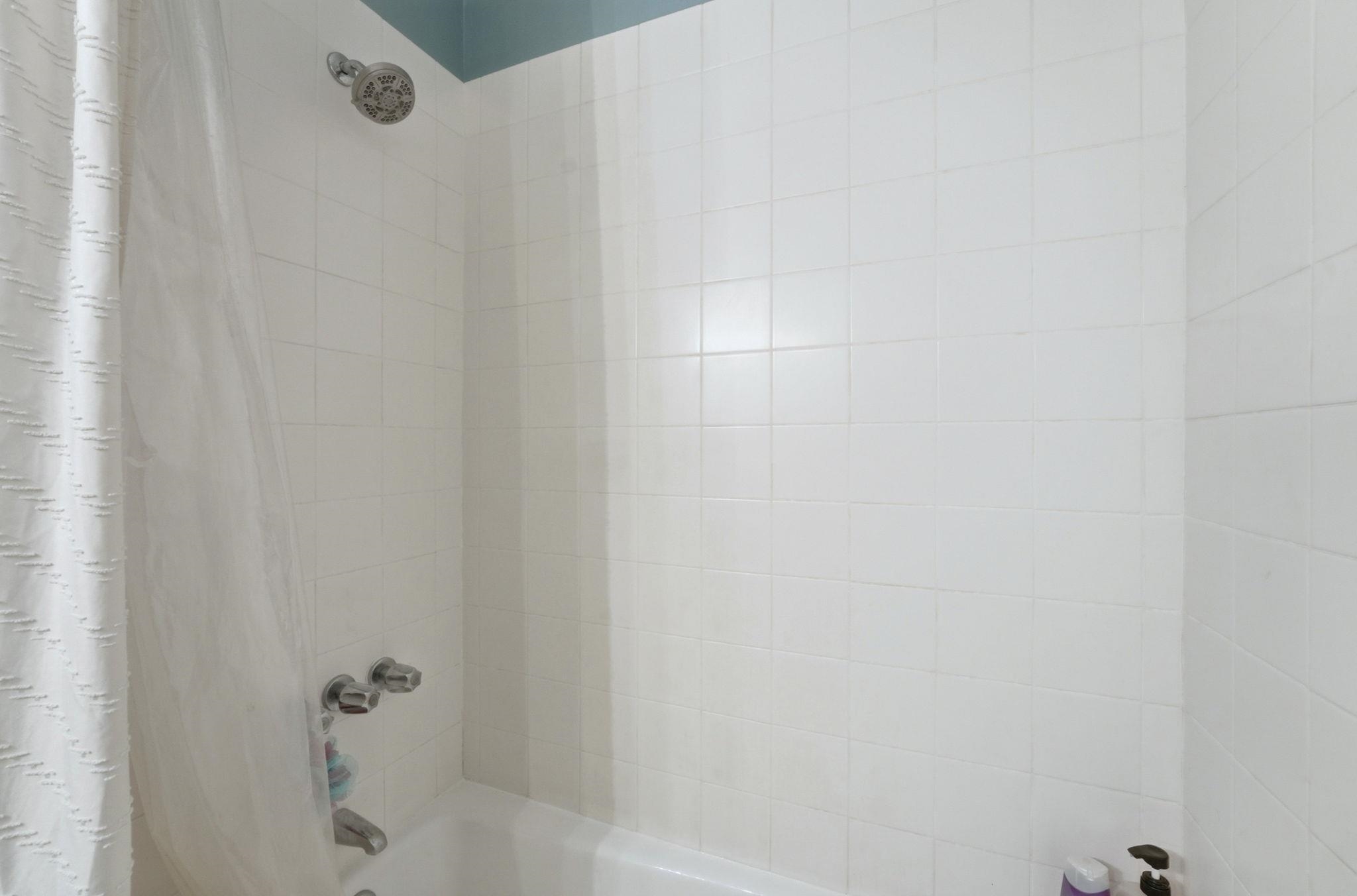 Bathroom view of shower / bath combination with curtain