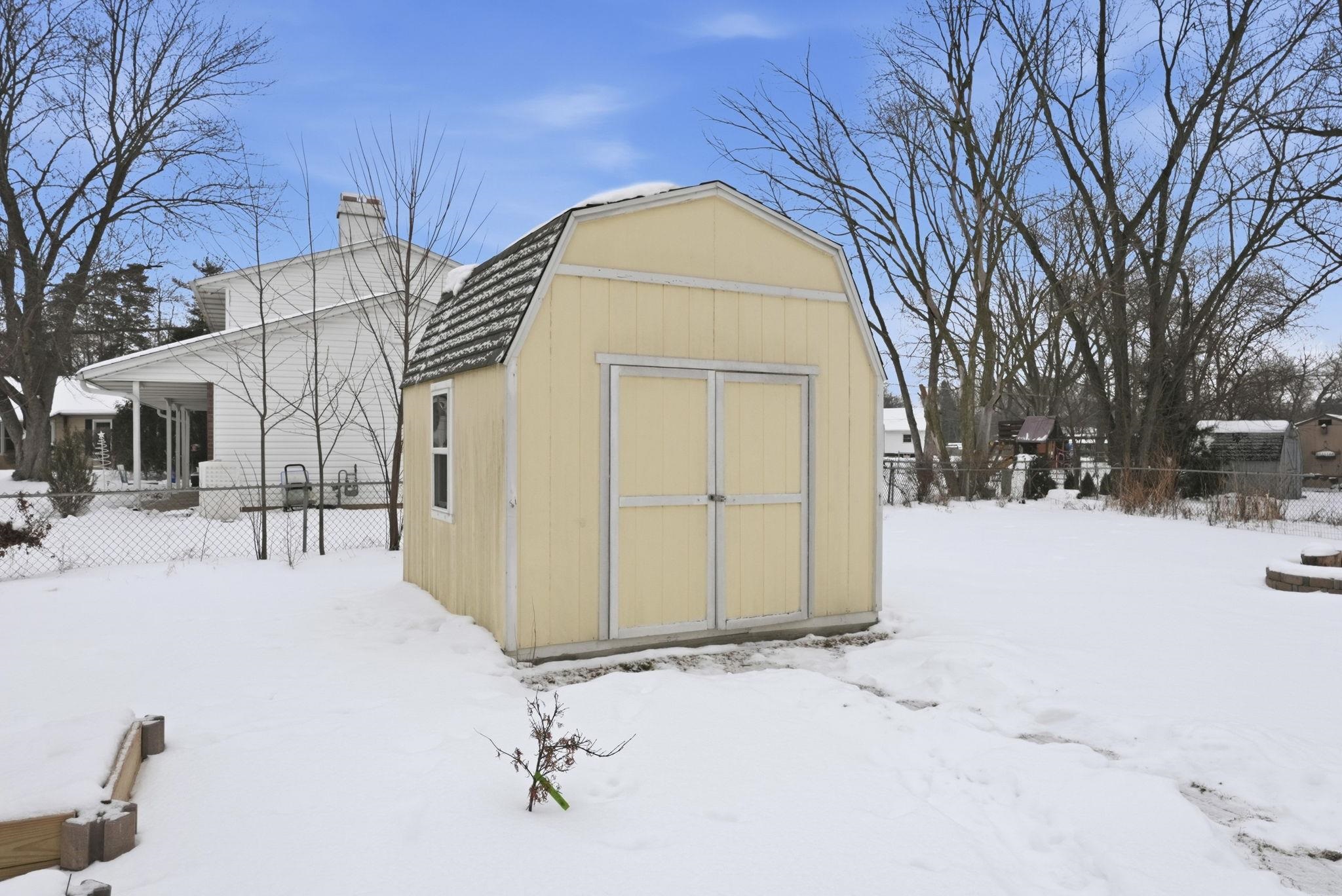 Snow covered structure featuring a shed