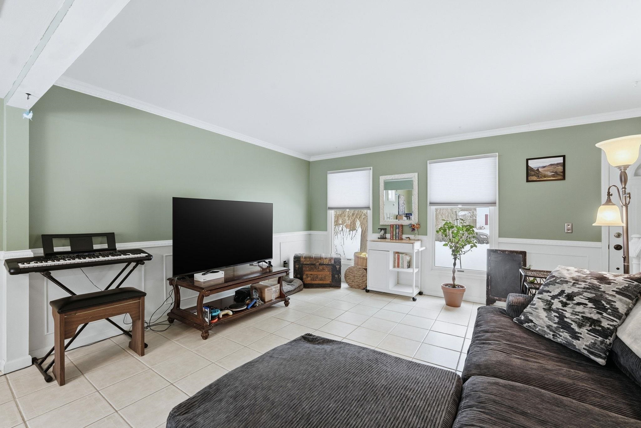 Living room featuring wainscoting, crown molding, and light tile patterned flooring