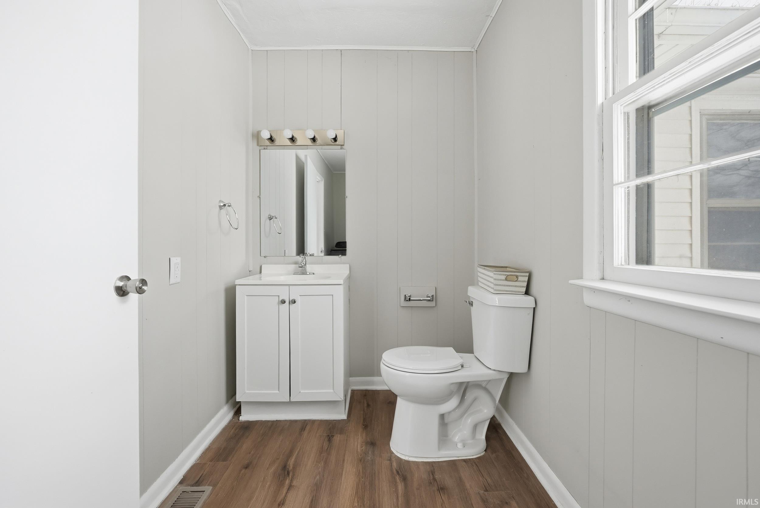 Bathroom featuring vanity, wooden walls, and dark wood-style flooring