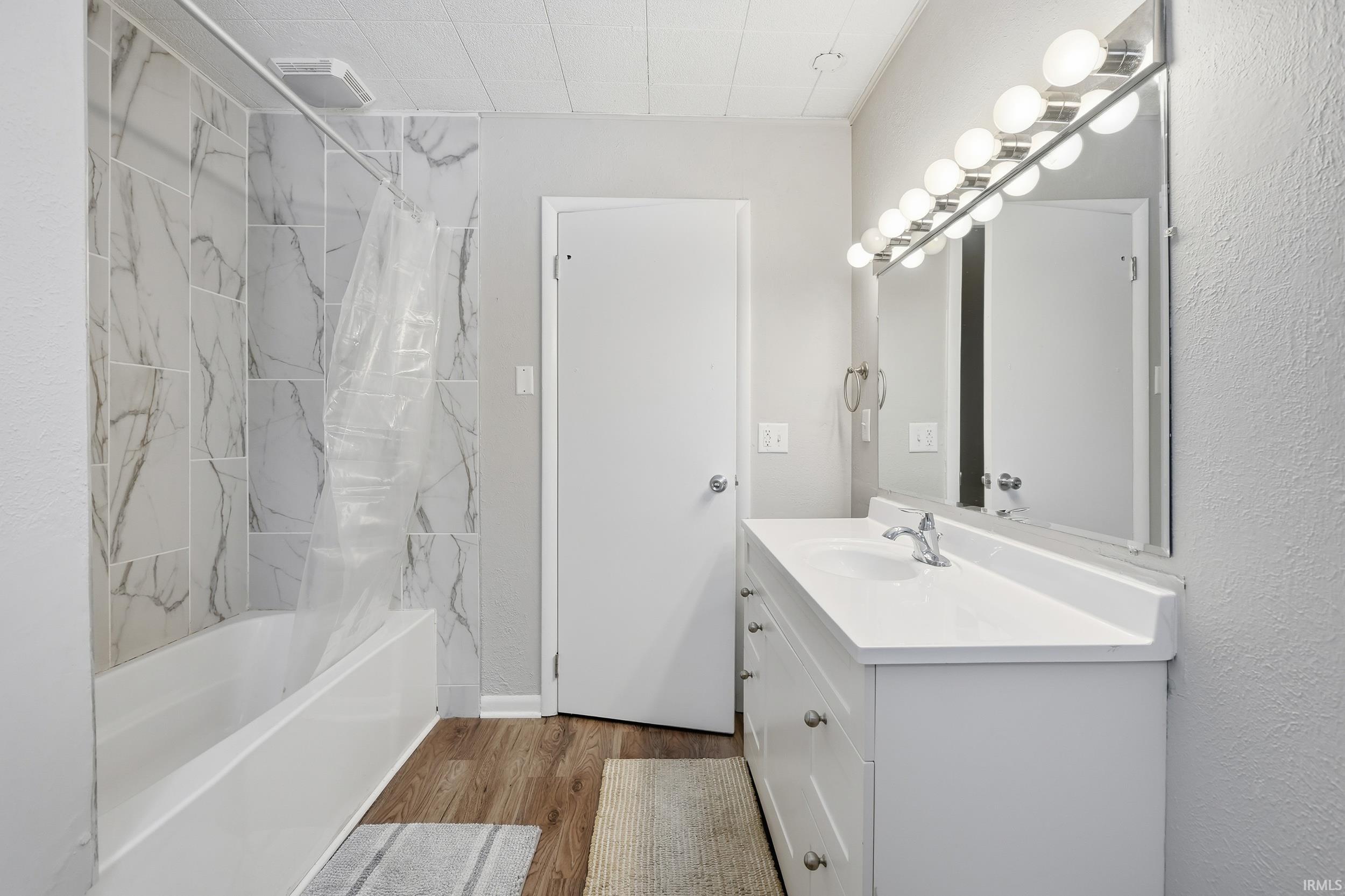Bathroom with vanity, shower / bathtub combination, and dark wood-type flooring