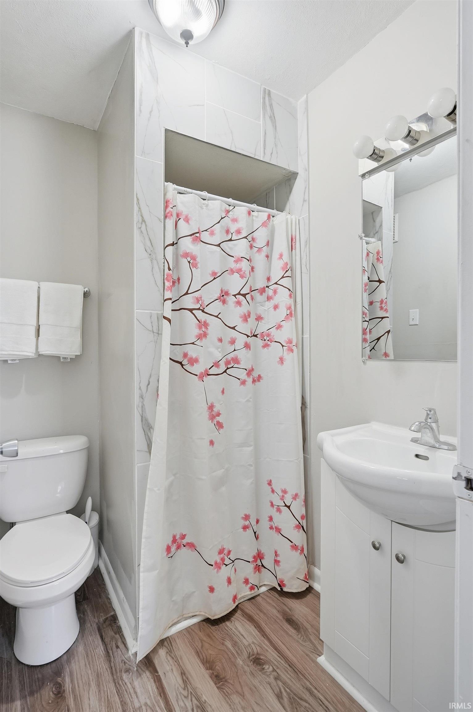 Full bathroom with a stall shower, vanity, and light wood-style flooring