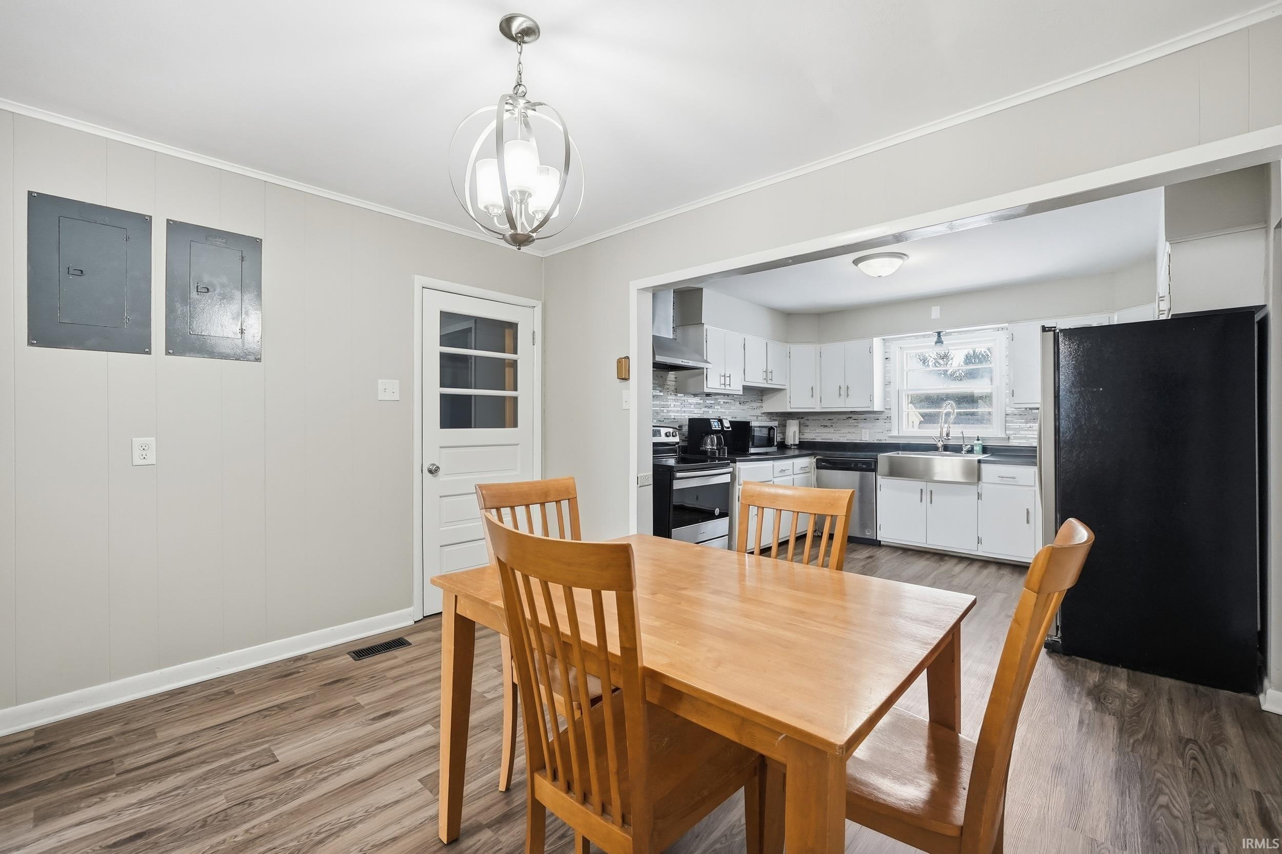 Dining room featuring a chandelier, crown molding, electric panel, and light wood-style floors