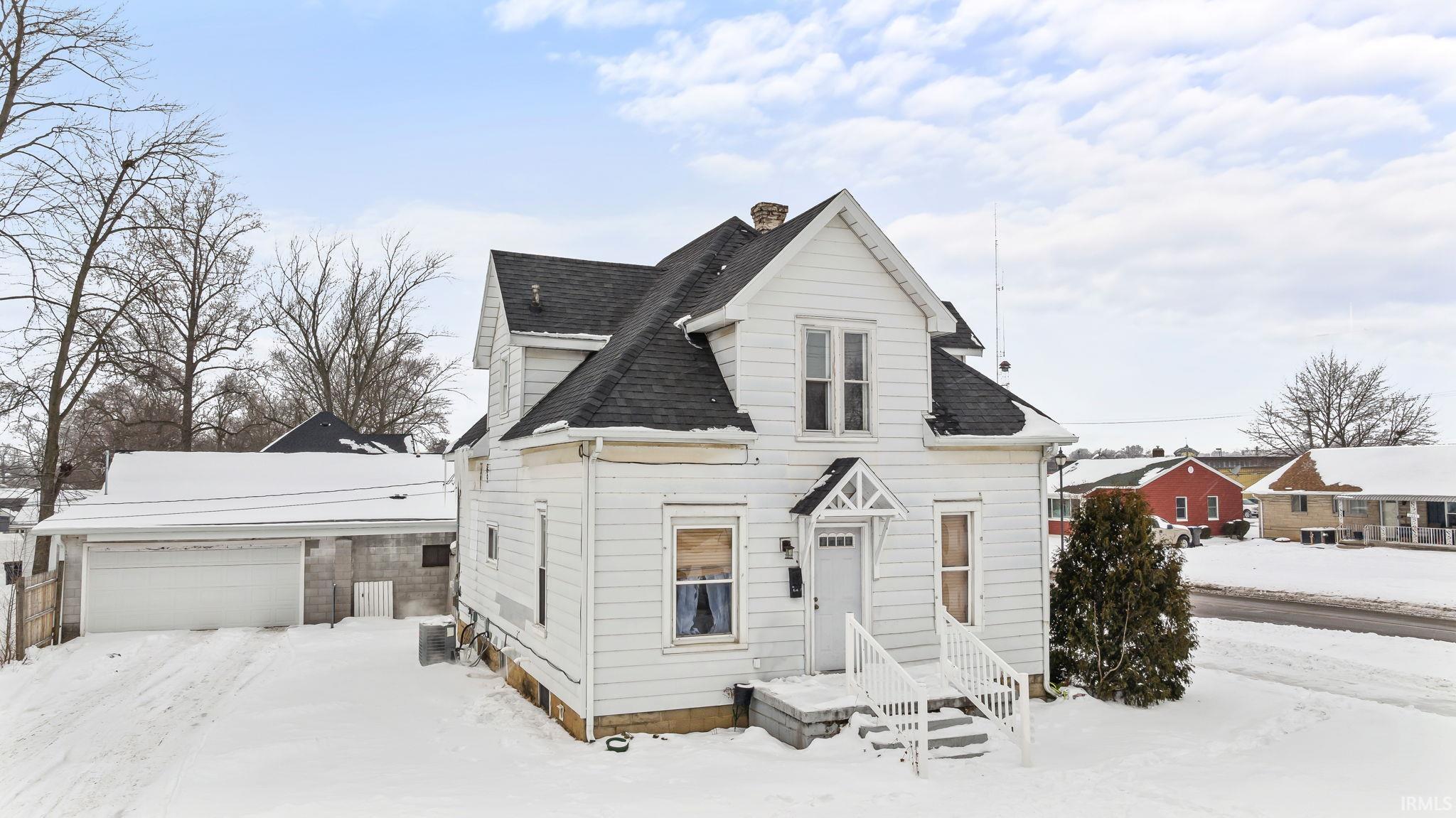 View of front facade with roof with shingles, a chimney, and a garage