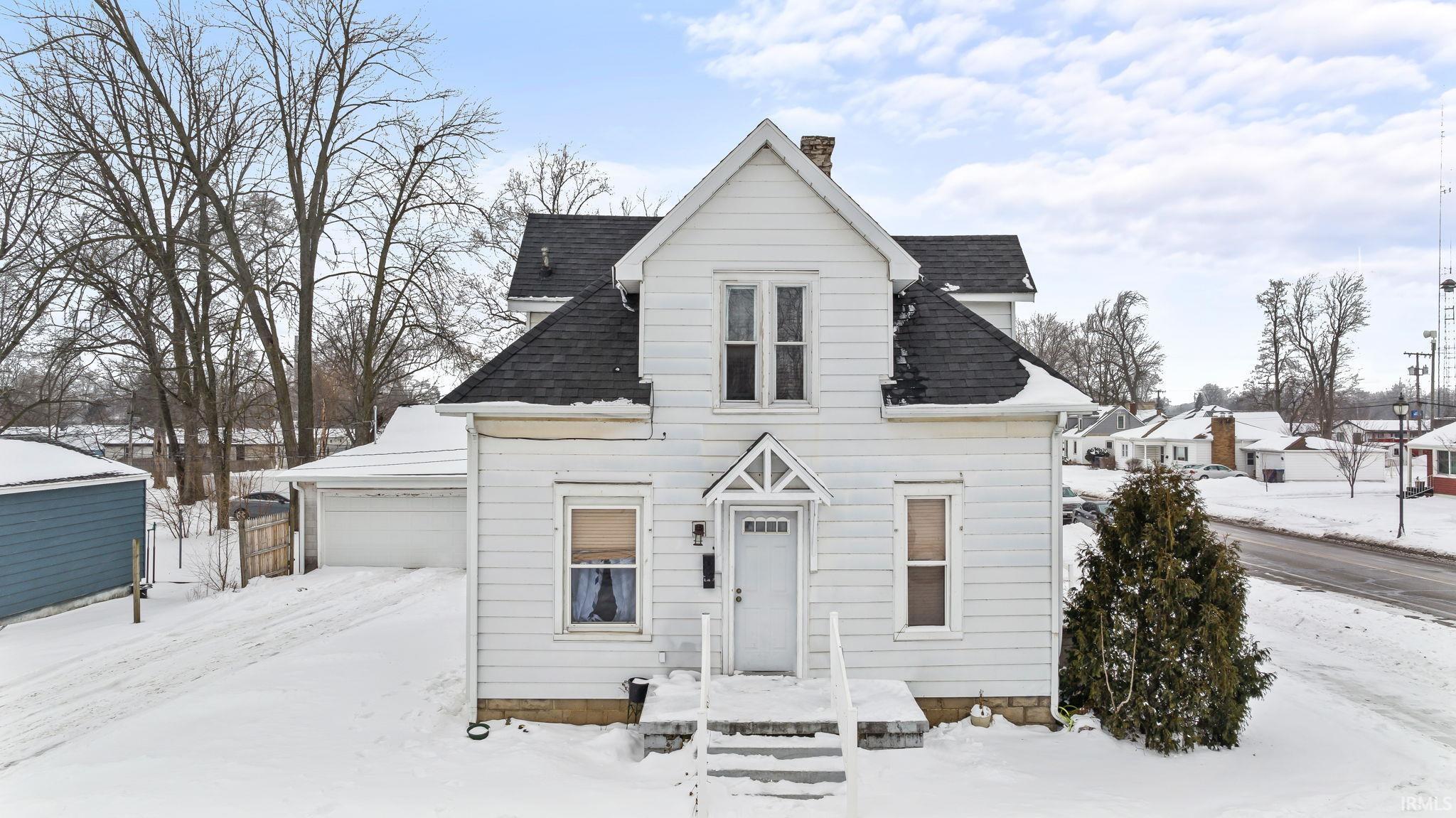 View of front of home with a shingled roof and a chimney