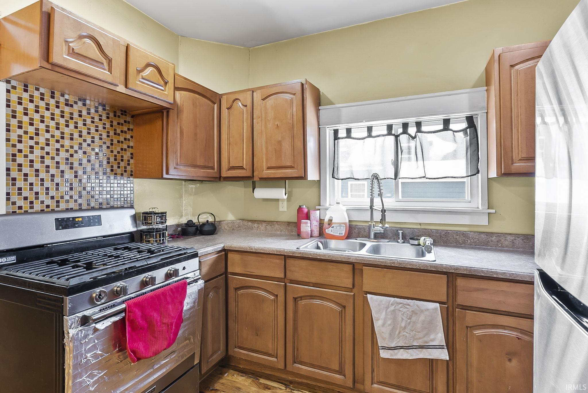 Kitchen with stainless steel appliances, wood finish cabinets, and light countertops