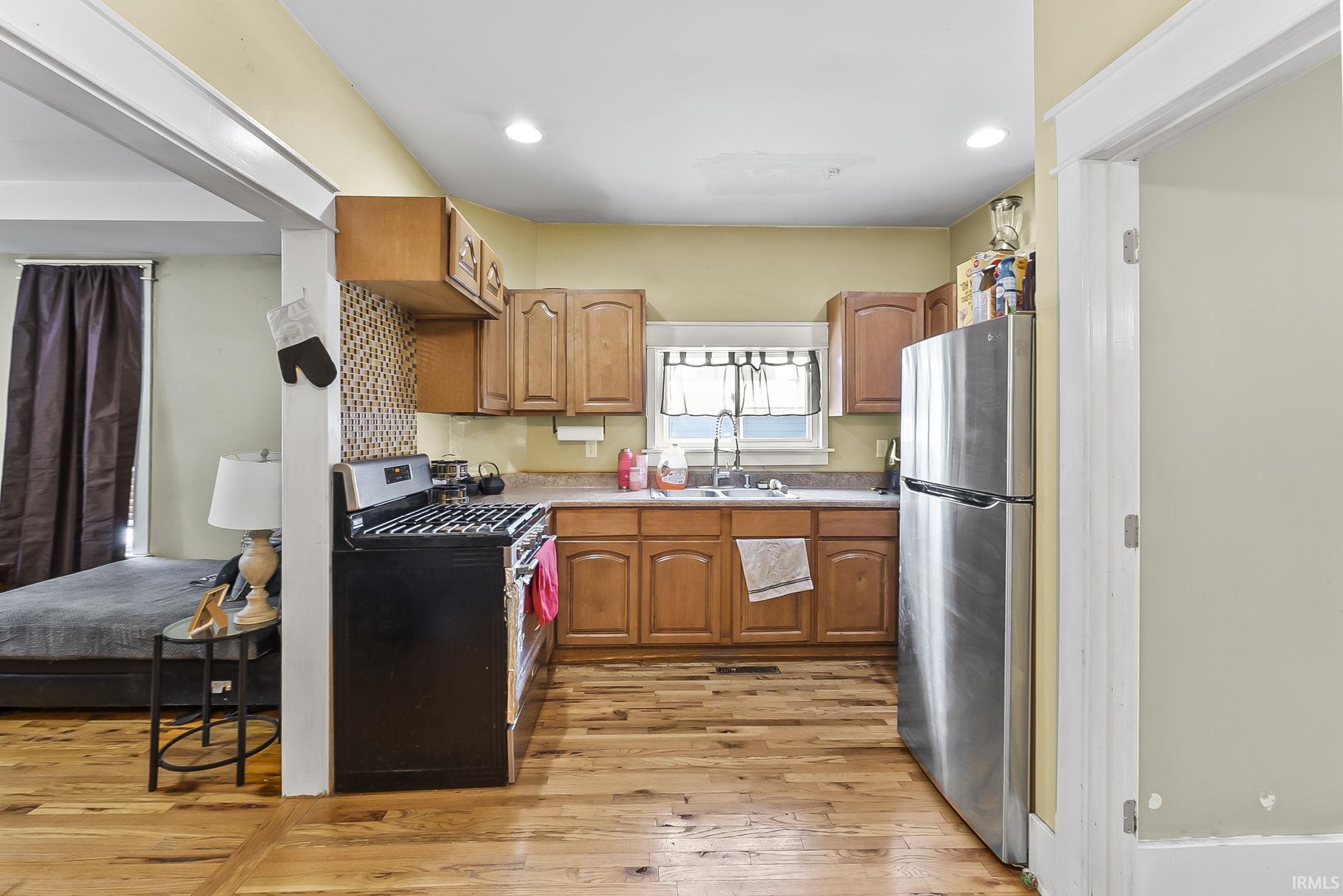 Kitchen with stainless steel appliances, light countertops, light wood-style floors, wood finish cabinetry, and recessed lighting