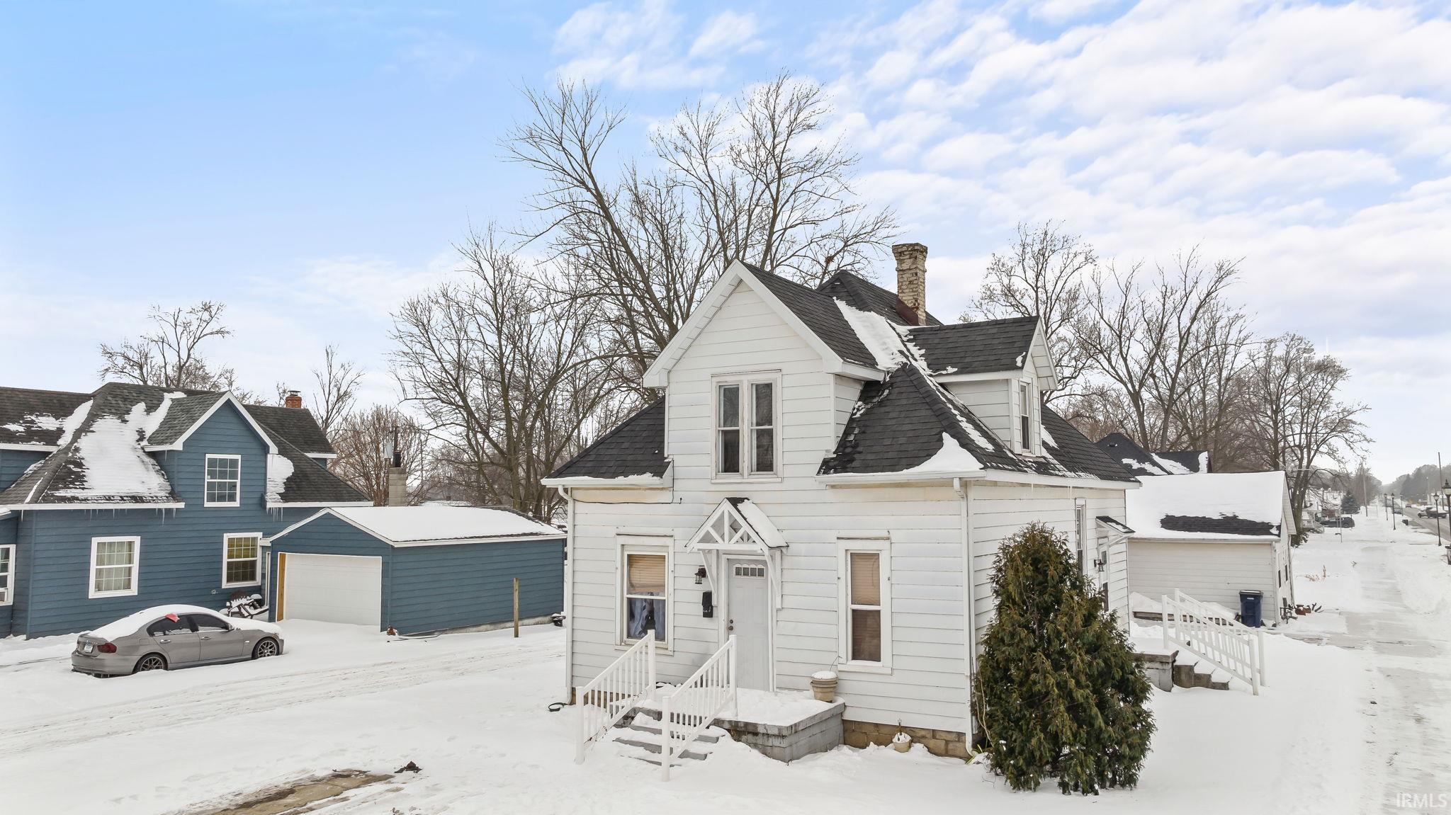 View of front facade with a chimney, a garage, and an outbuilding
