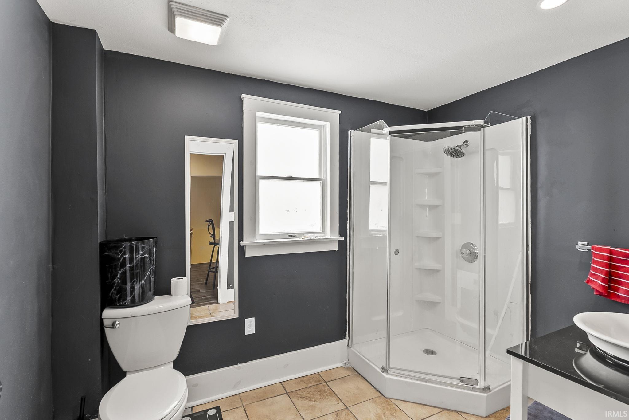 Bathroom featuring a shower stall, light tile patterned flooring, and vanity
