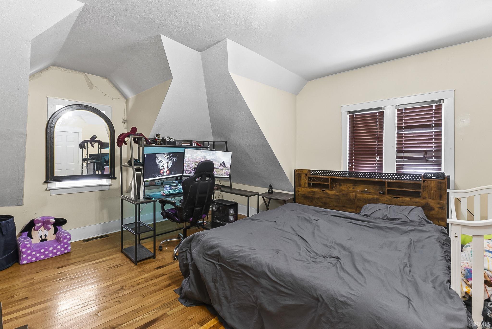 Bedroom featuring lofted ceiling and light wood-style floors