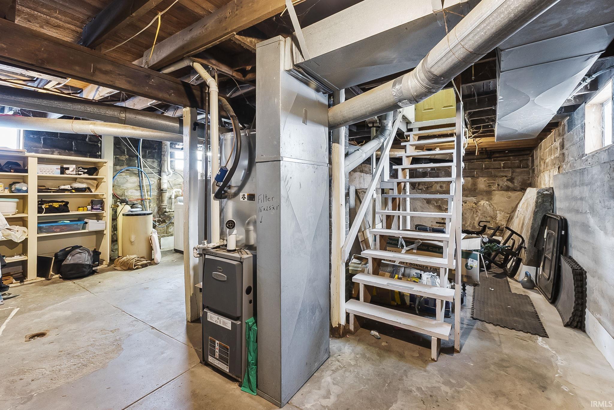 Unfinished basement featuring stairway and heating unit
