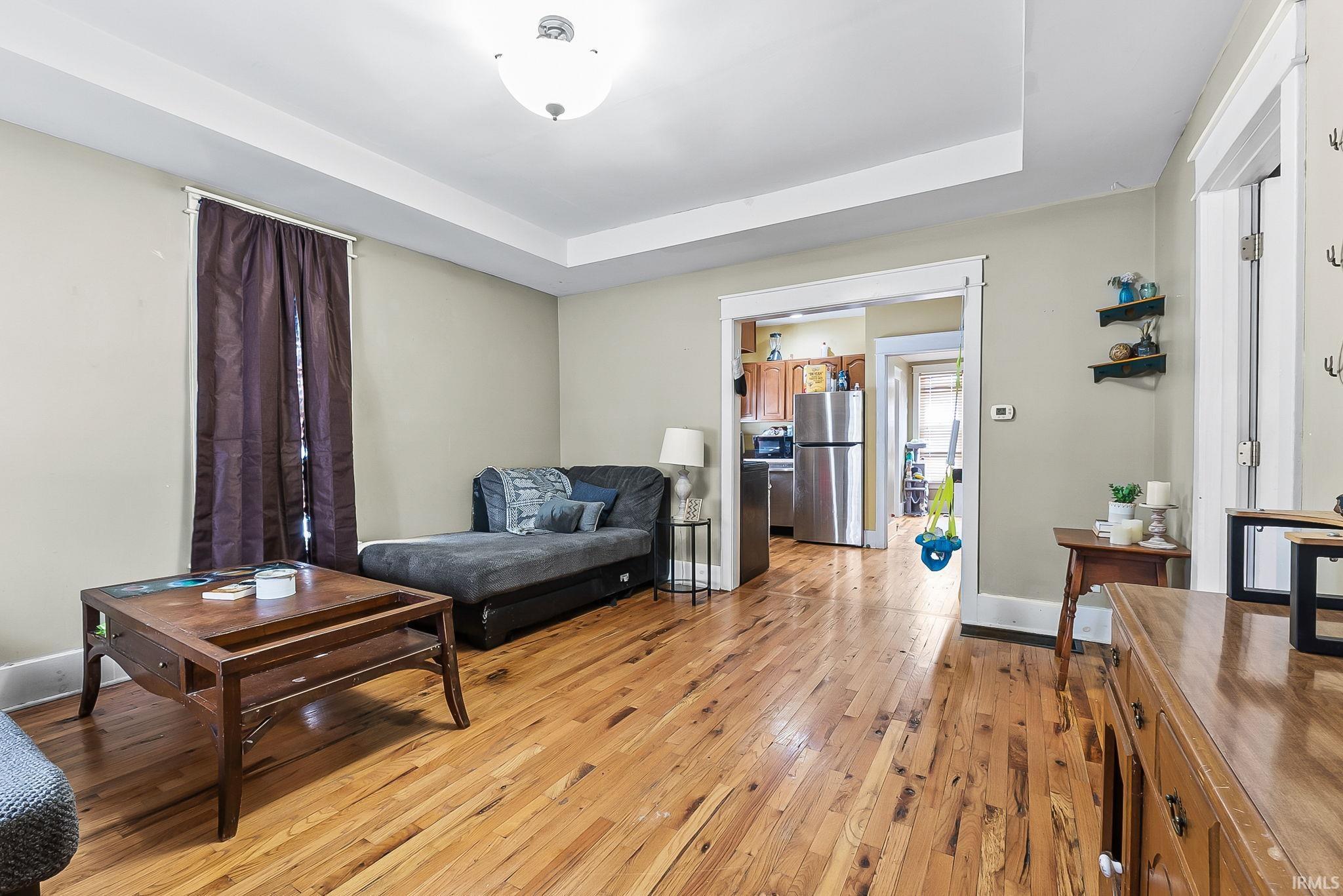Living area featuring a tray ceiling and light wood-type flooring