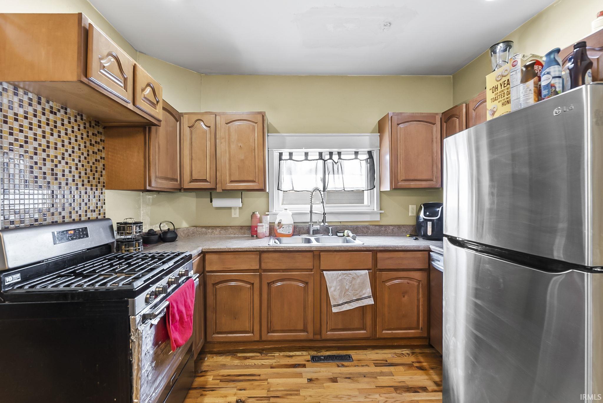 Kitchen featuring stainless steel appliances, wood finish cabinets, light wood-type flooring, and light countertops