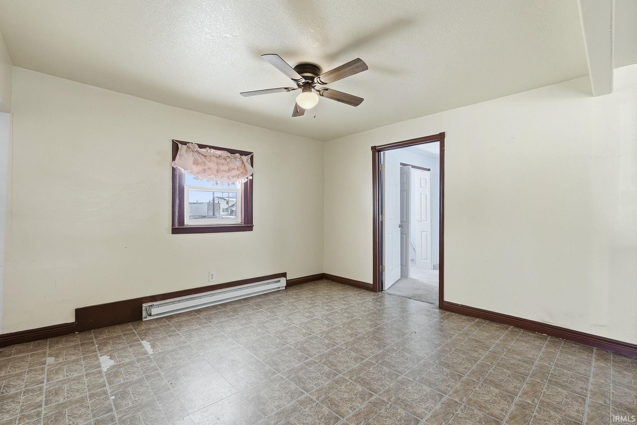 Empty room featuring baseboard heating, a ceiling fan, and a textured ceiling