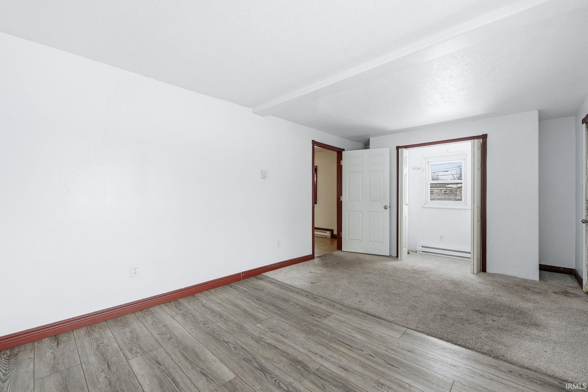 Unfurnished bedroom with baseboard heating and light wood-style flooring