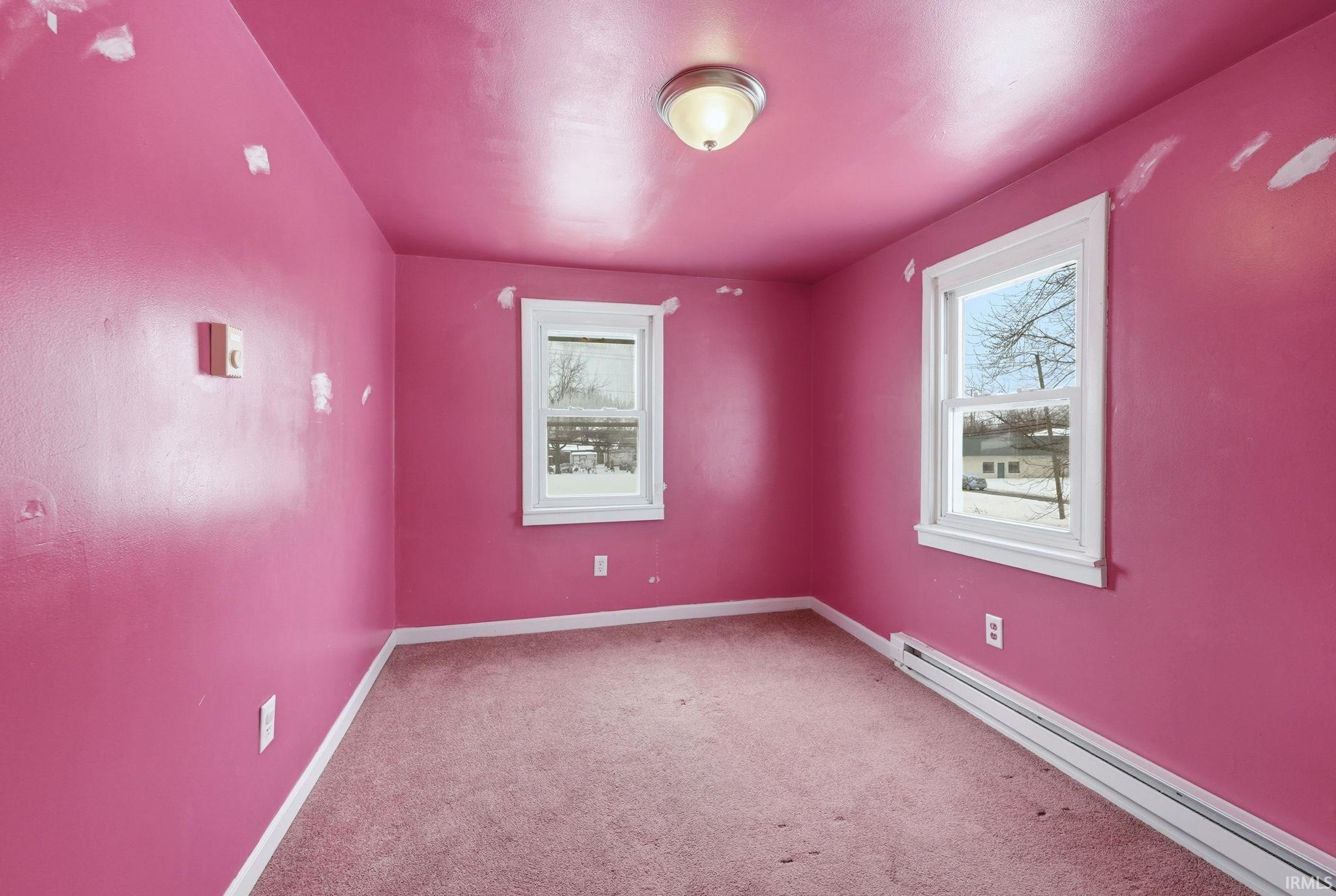 Unfurnished room featuring a baseboard radiator and carpet