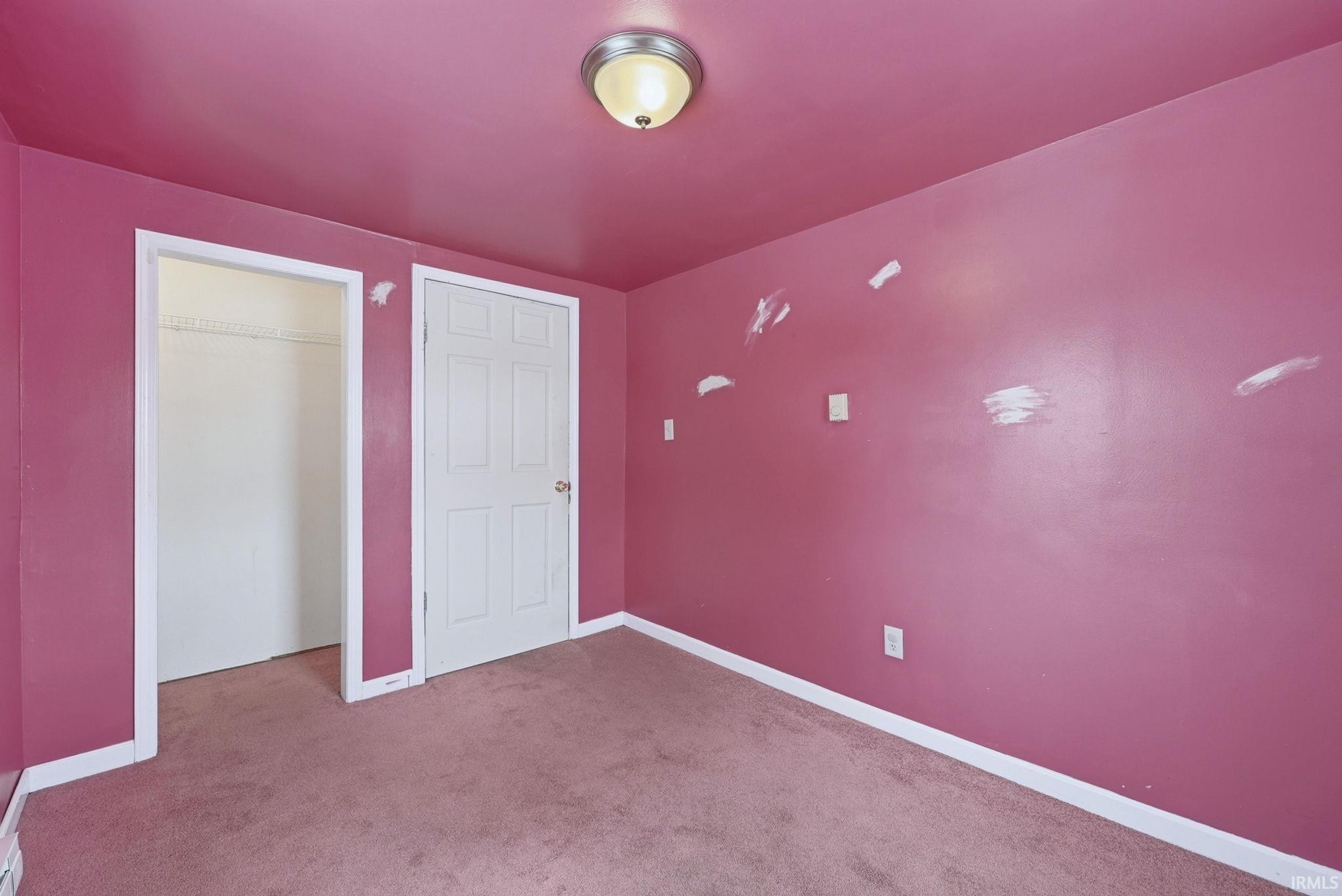 Unfurnished bedroom featuring dark carpet and a closet