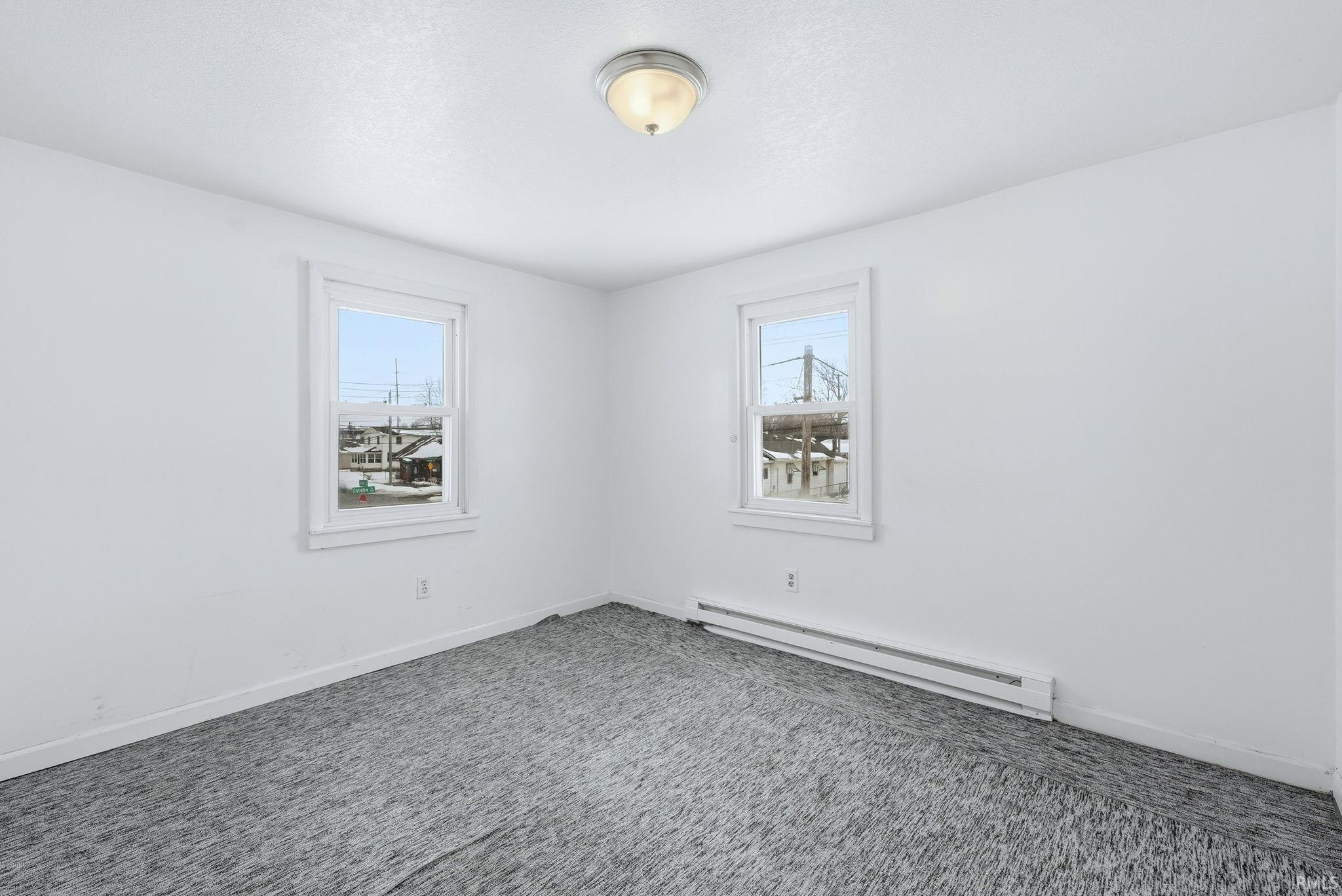Carpeted empty room featuring baseboard heating and healthy amount of natural light