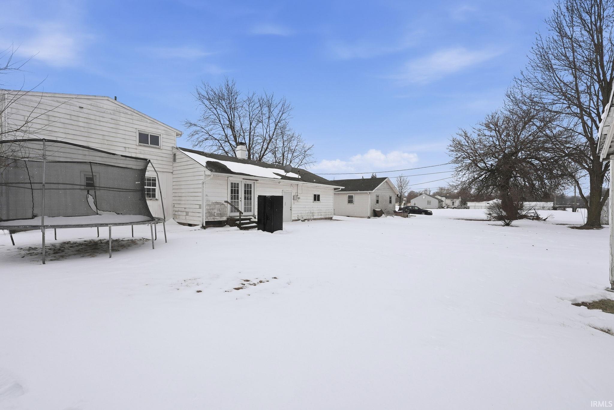 Snow covered property featuring a chimney, a trampoline, and french doors