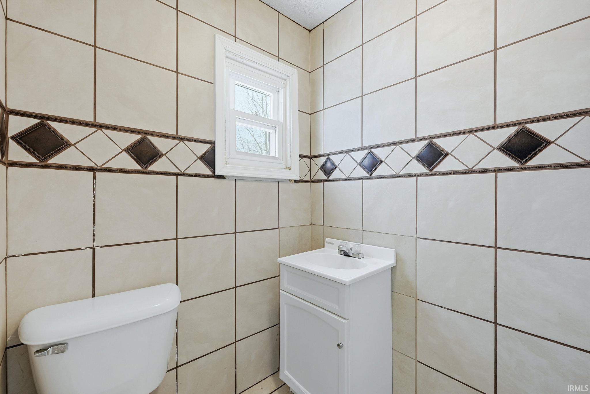 Half bathroom featuring tile walls and vanity