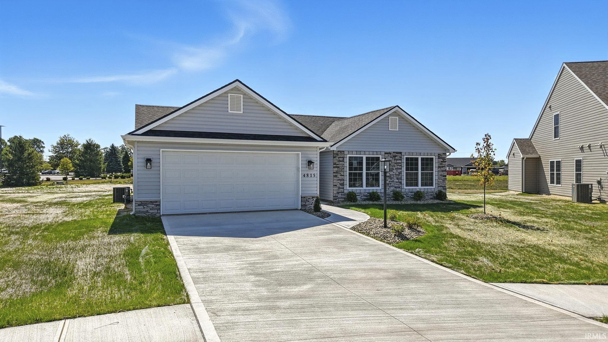 View of front of home with stone siding, a front yard, driveway, and an attached garage
