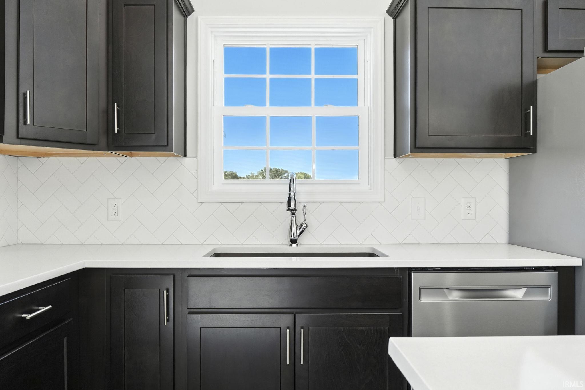 Kitchen featuring light stone counters and stainless steel dishwasher