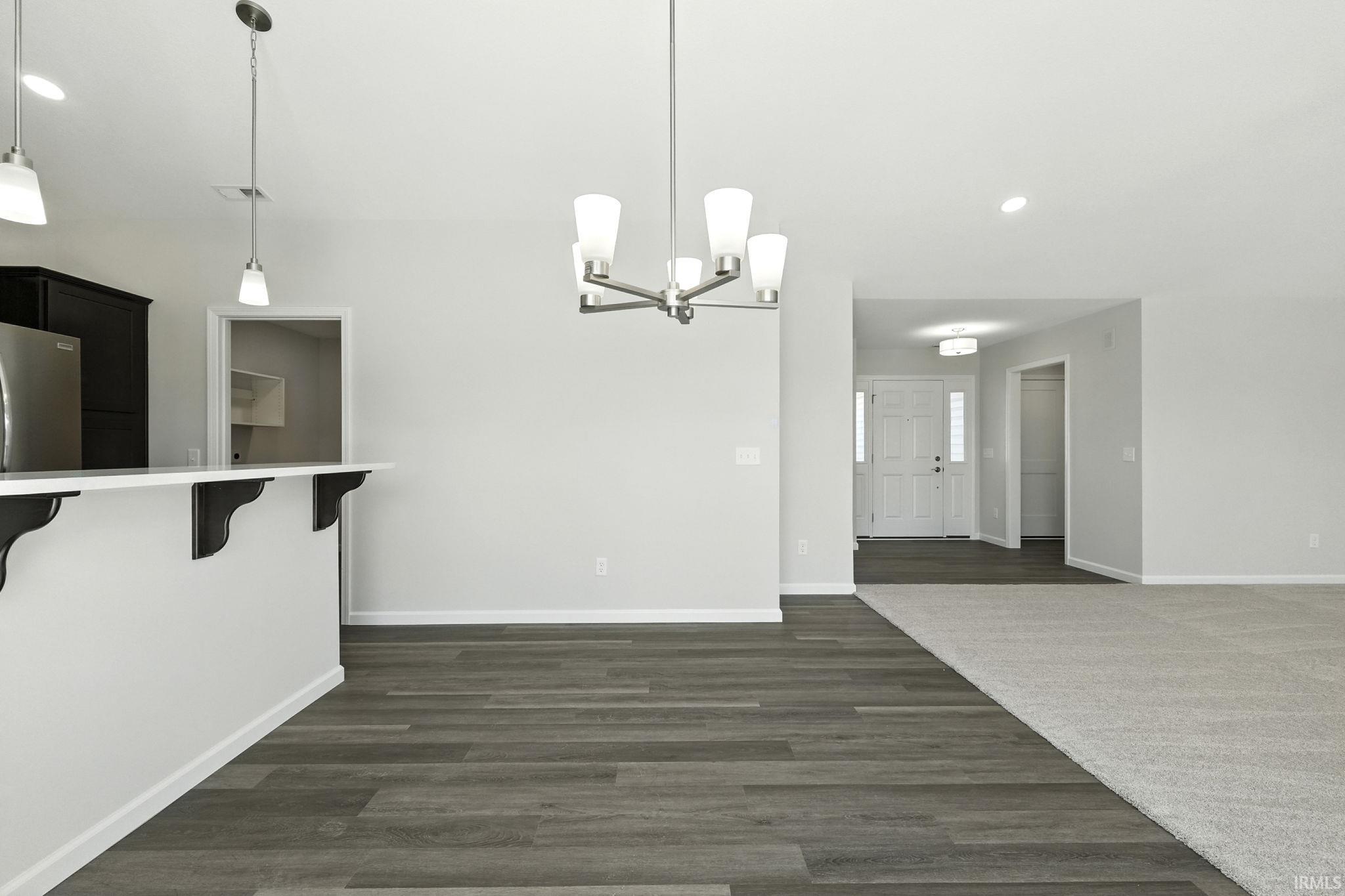 Unfurnished dining area featuring dark wood finished floors and hanging lights