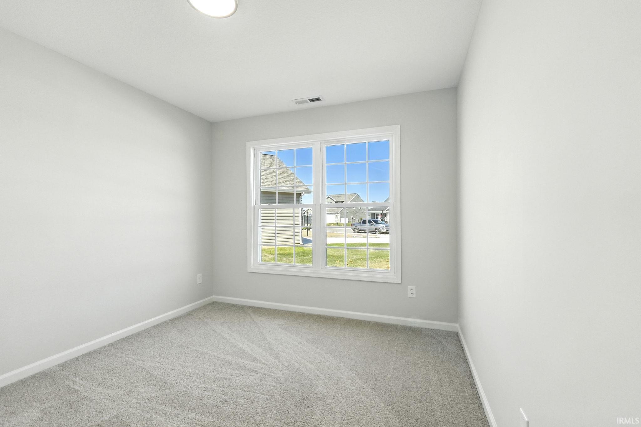 Empty room with light colored carpet and baseboards