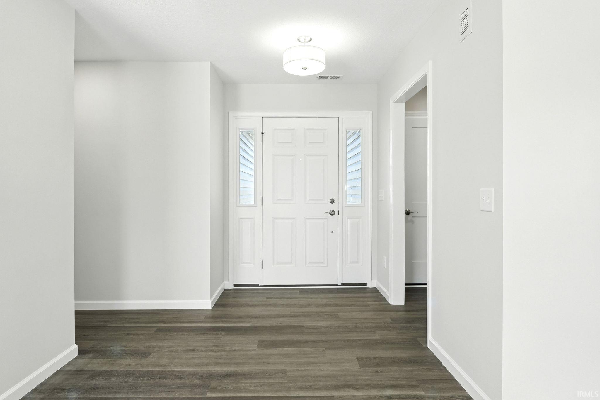 Foyer with dark wood-type flooring and baseboards