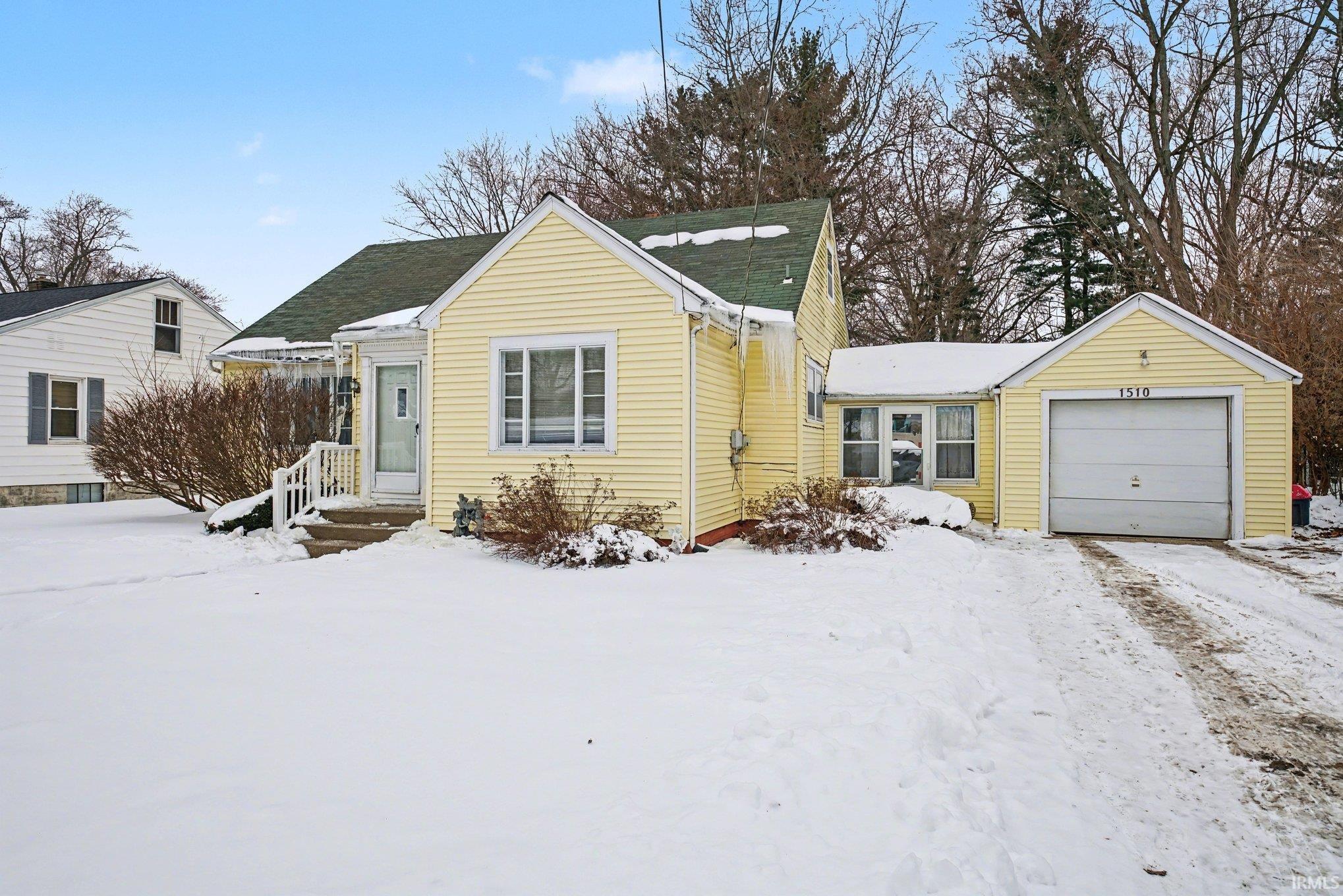 View of front of property featuring a garage and roof with shingles