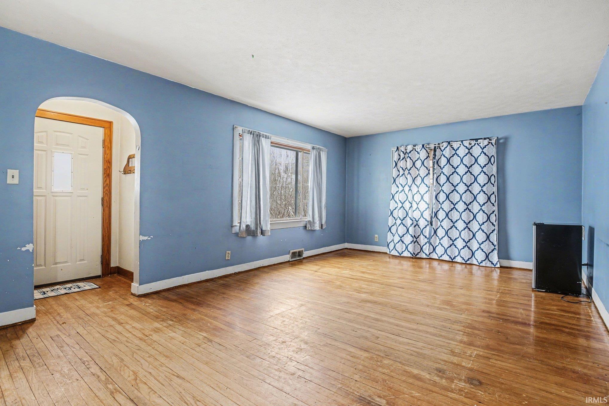 Empty room featuring arched walkways and light wood-style flooring