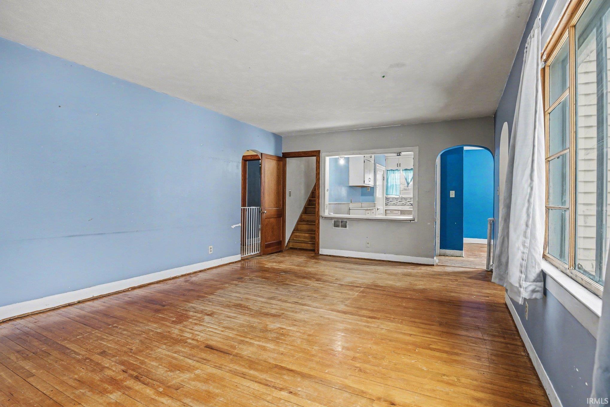 Spare room featuring arched walkways and hardwood / wood-style floors