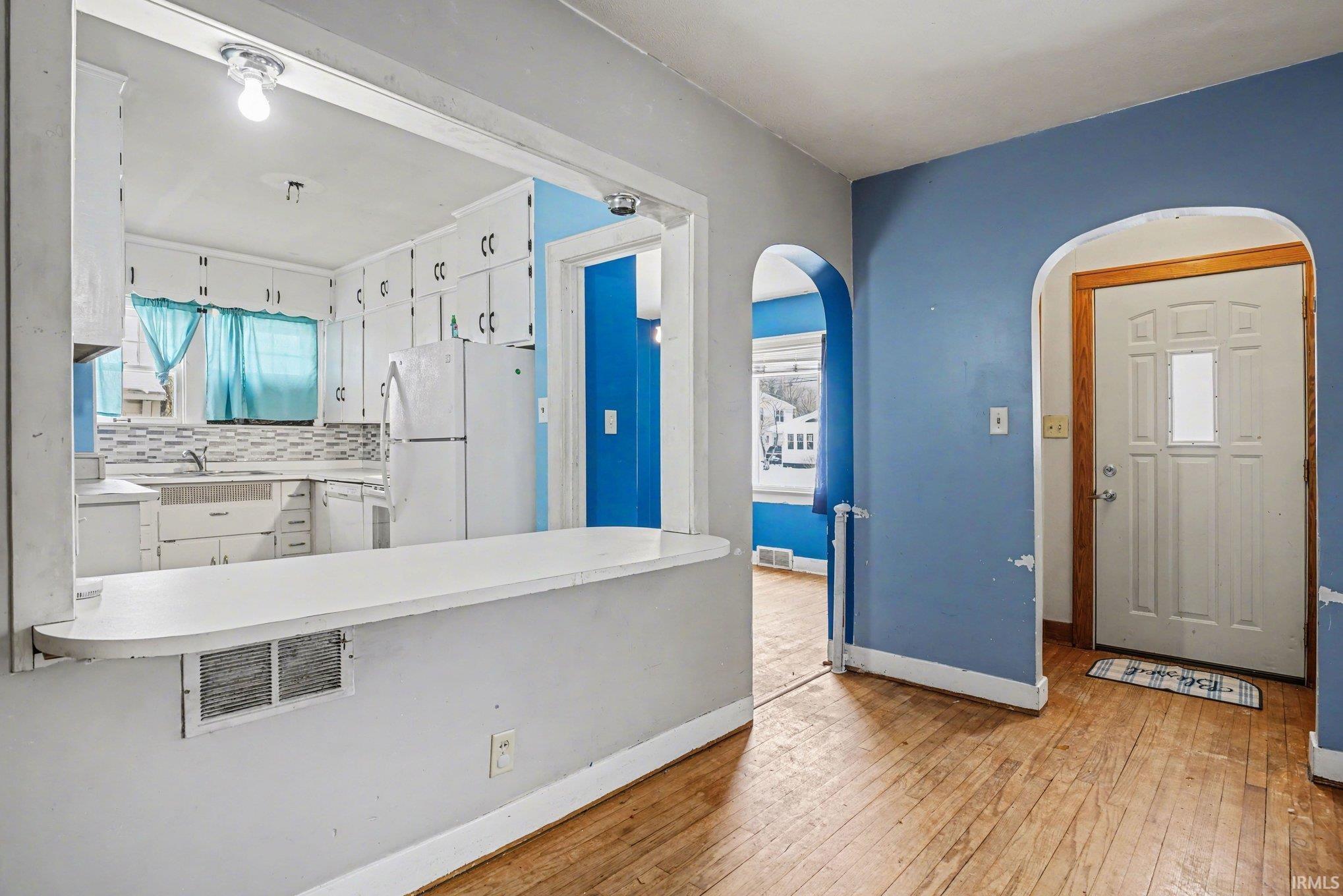 Foyer entrance with light wood-style floors and arched walkways