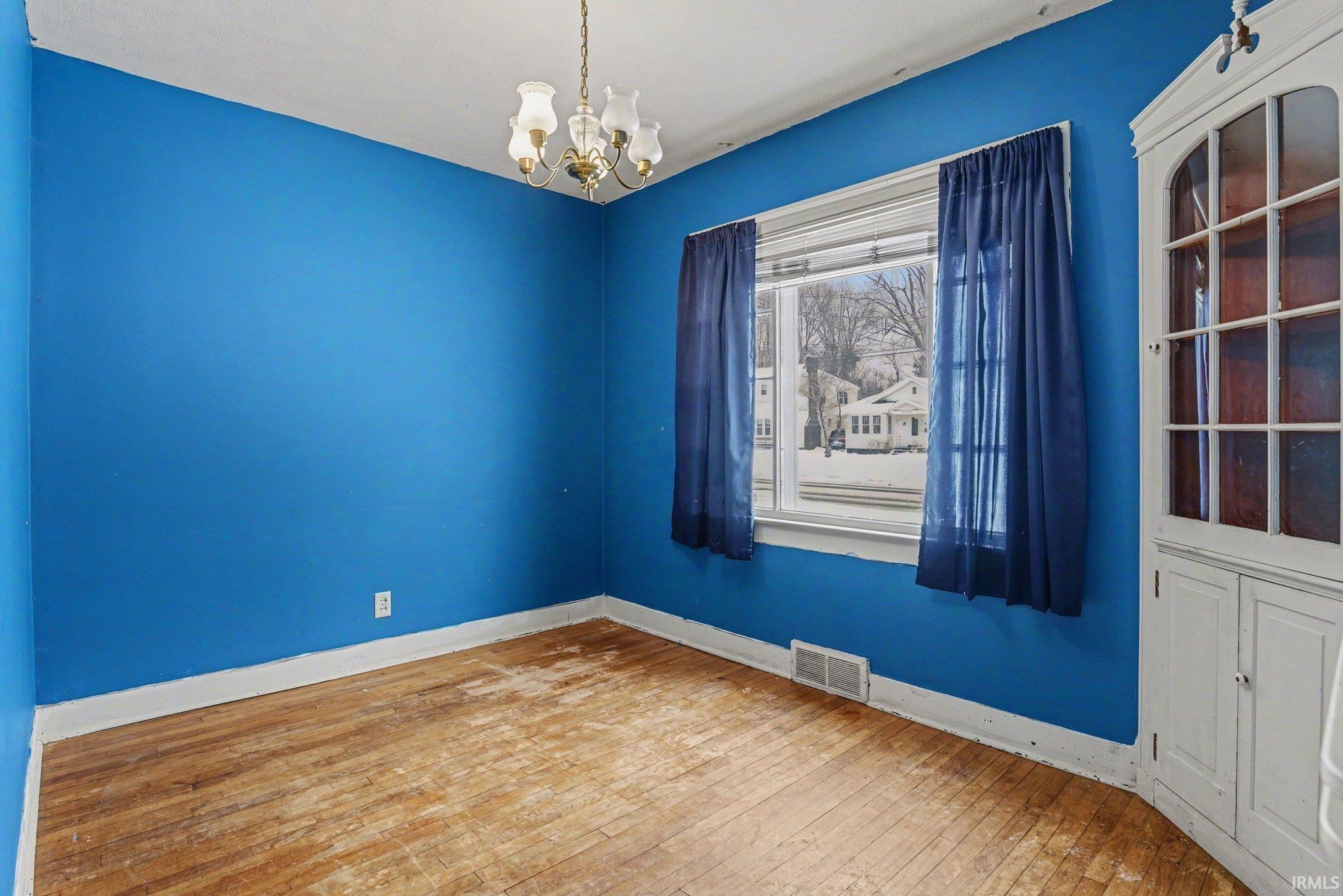 Unfurnished room featuring hardwood / wood-style floors and a chandelier