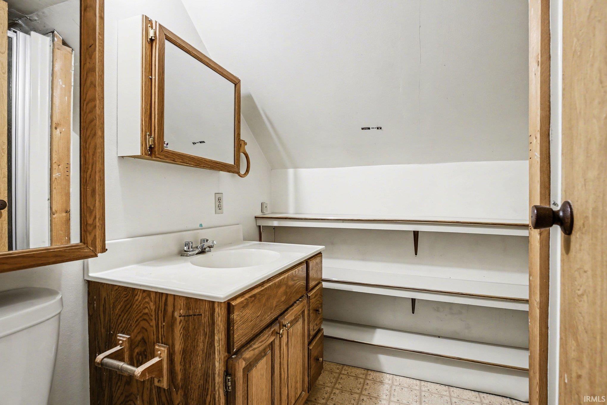 Bathroom with light flooring, vanity, and lofted ceiling