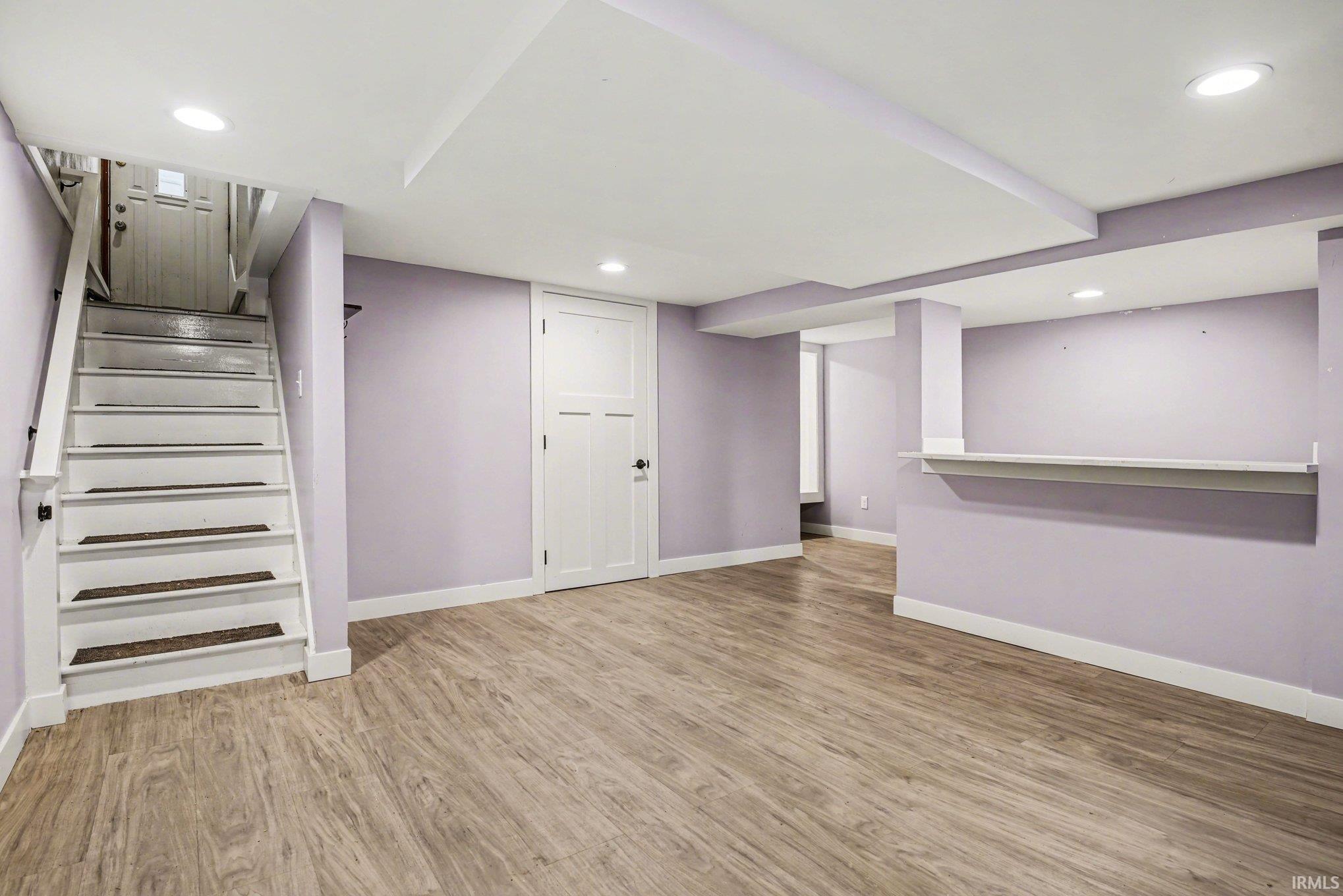 Finished basement with light wood-style flooring and recessed lighting