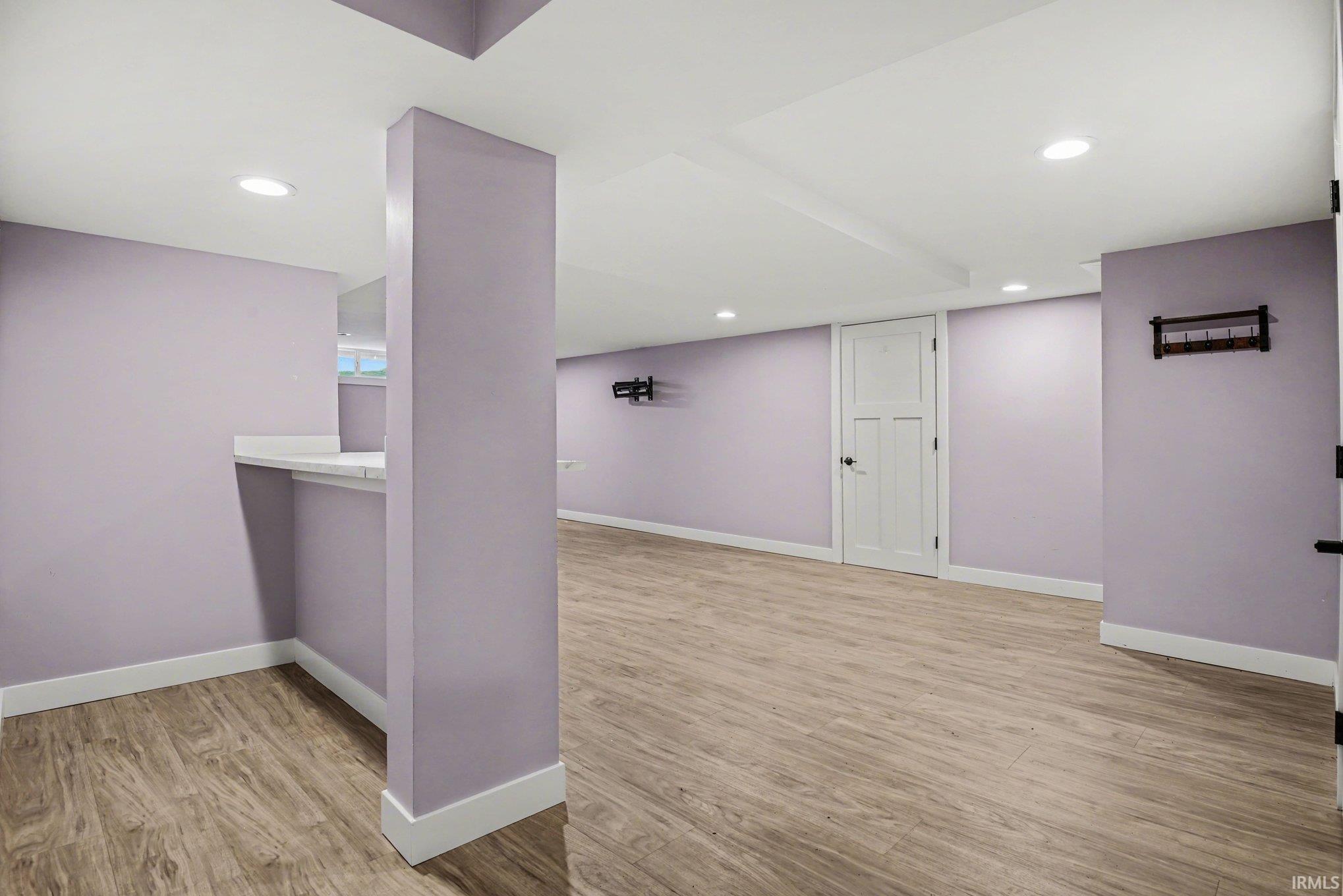 Finished below grade area with light wood-style flooring and recessed lighting