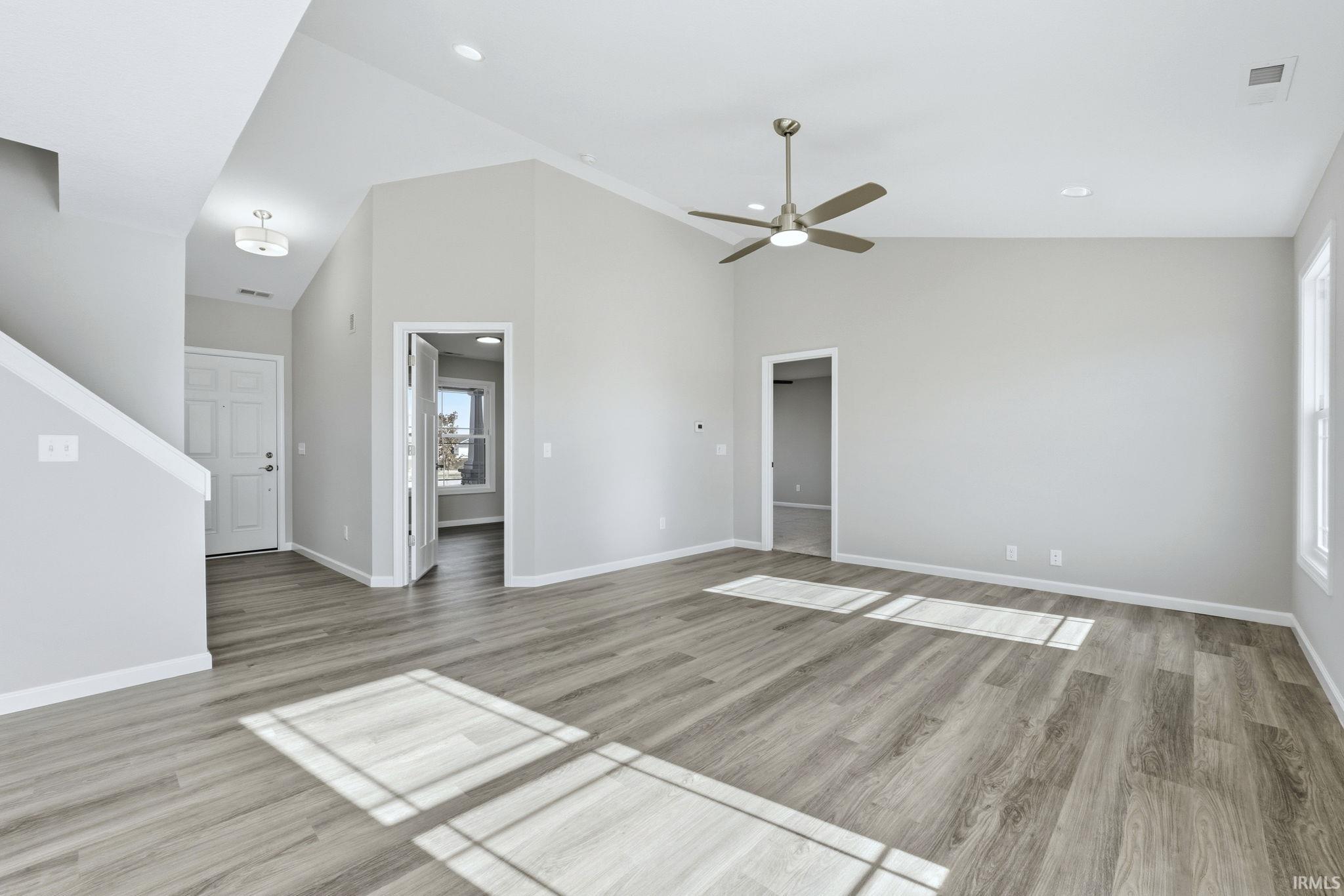 Unfurnished living room featuring light wood-type flooring, lofted ceiling, ceiling fan, and recessed lighting