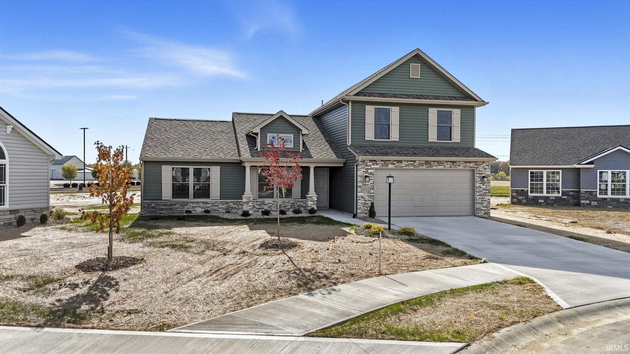 Craftsman inspired home featuring stone siding, a garage, driveway, and a shingled roof