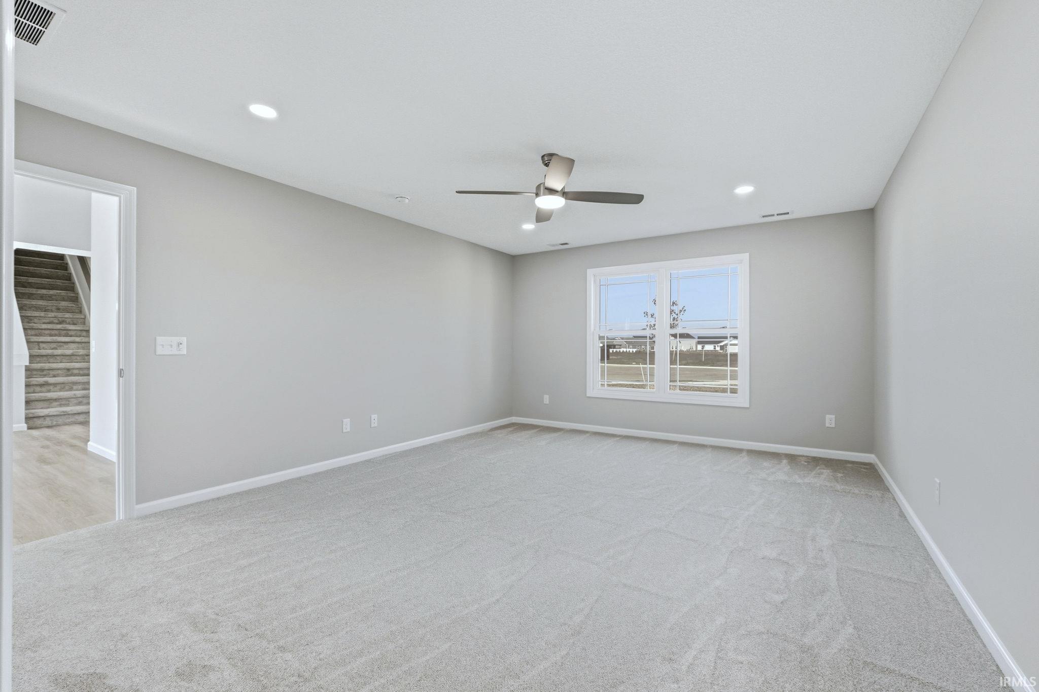 Empty room featuring light colored carpet, ceiling fan, and recessed lighting
