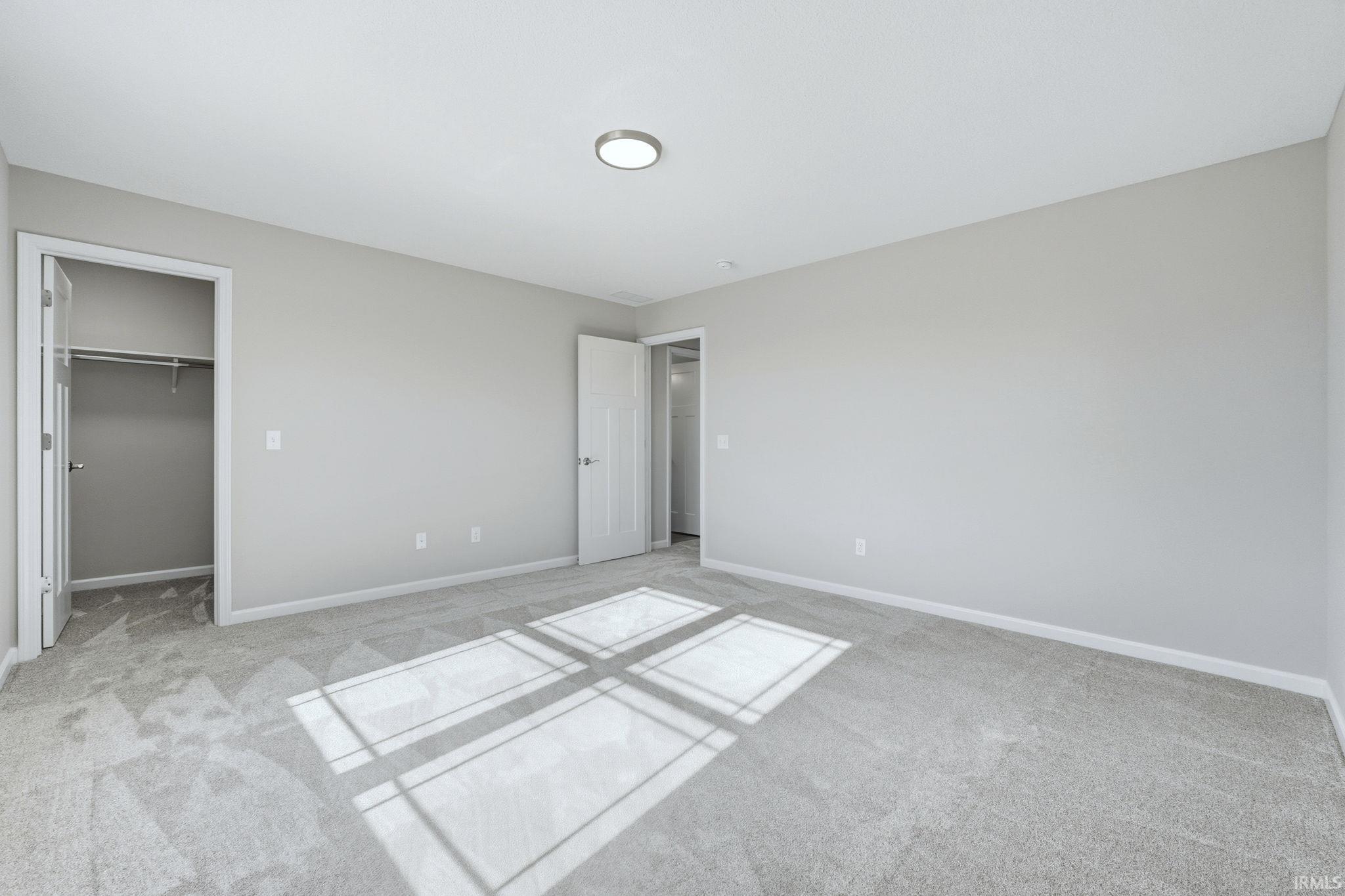 Unfurnished bedroom featuring a walk in closet and carpet flooring