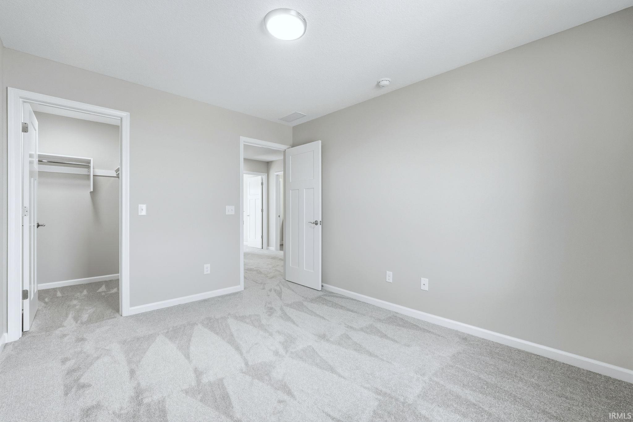 Unfurnished bedroom featuring a spacious closet and light carpet