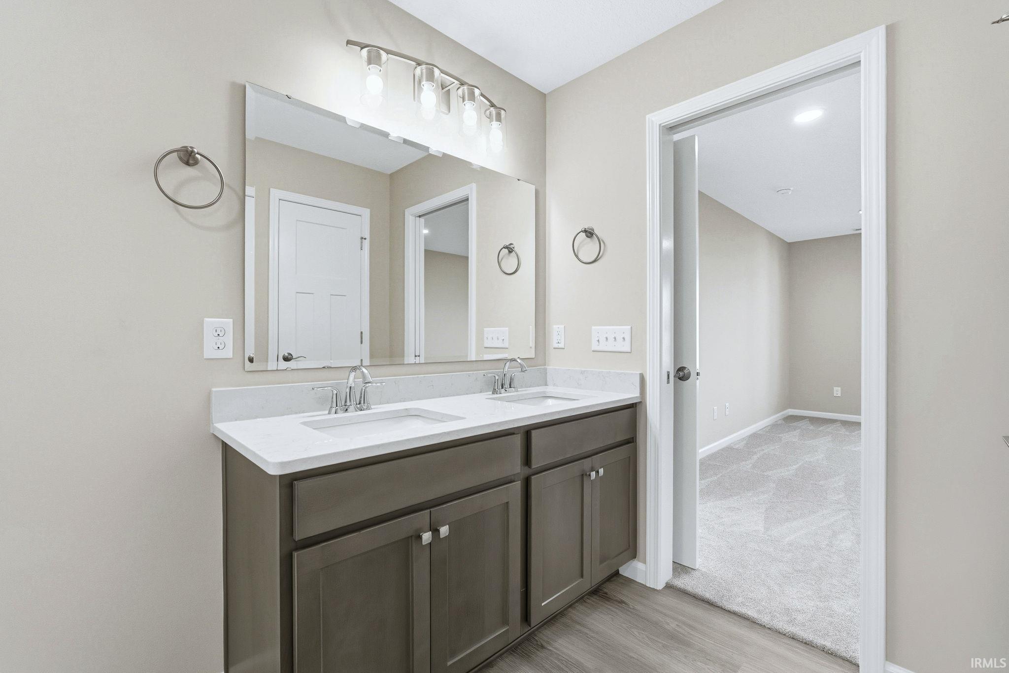 Full bath with double vanity and light wood finished floors