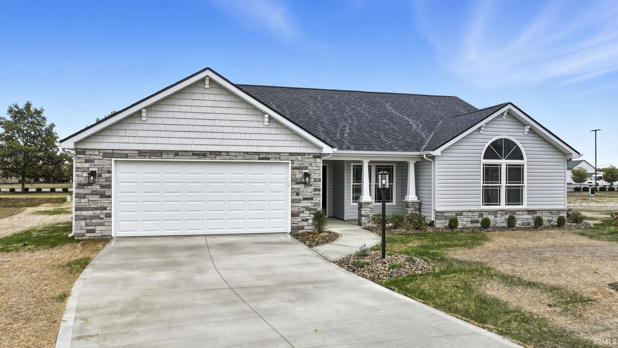 View of front facade featuring stone siding, covered porch, concrete driveway, a shingled roof, and a garage