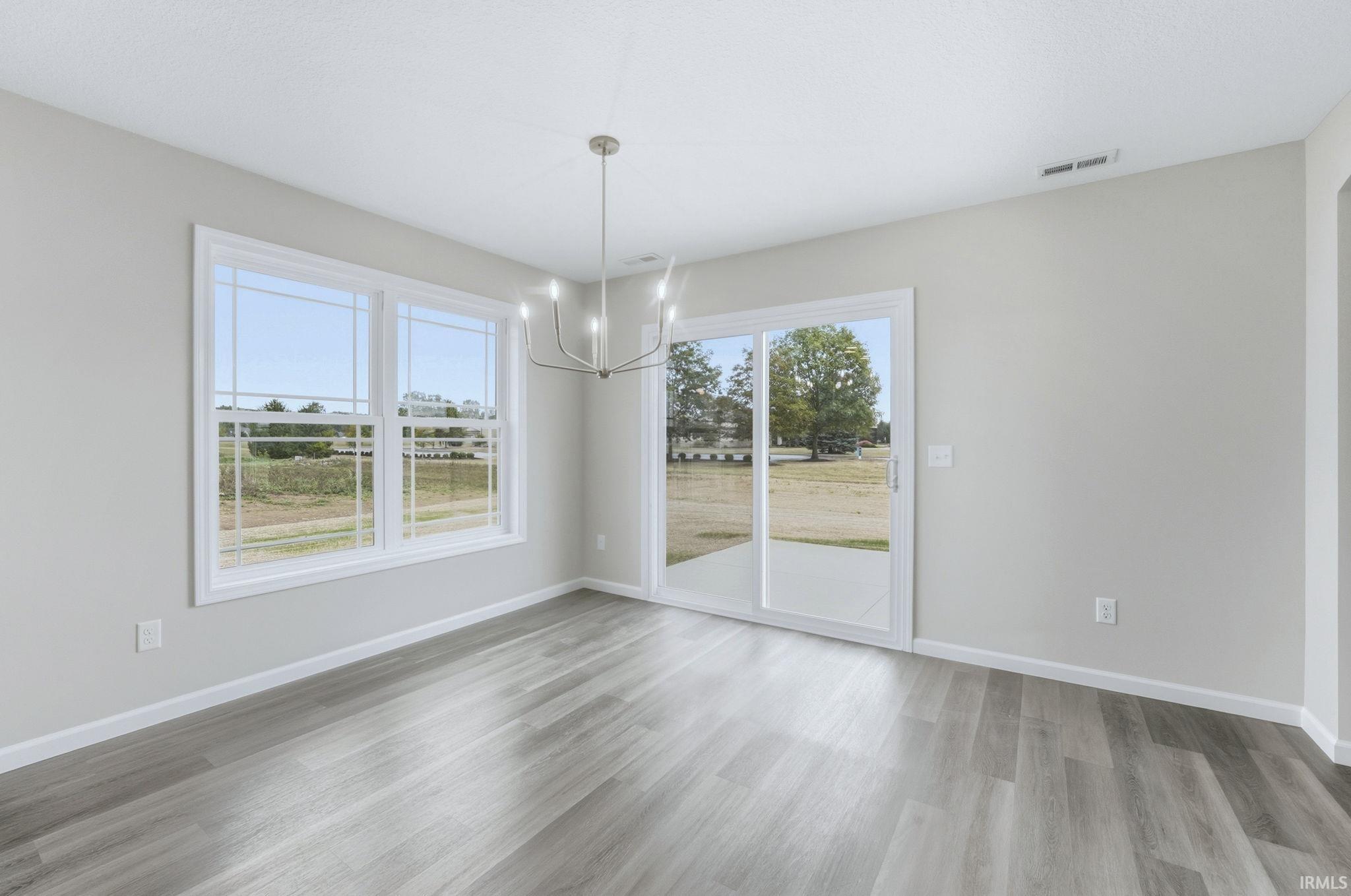 Unfurnished dining area with hanging lights and light wood-style floors