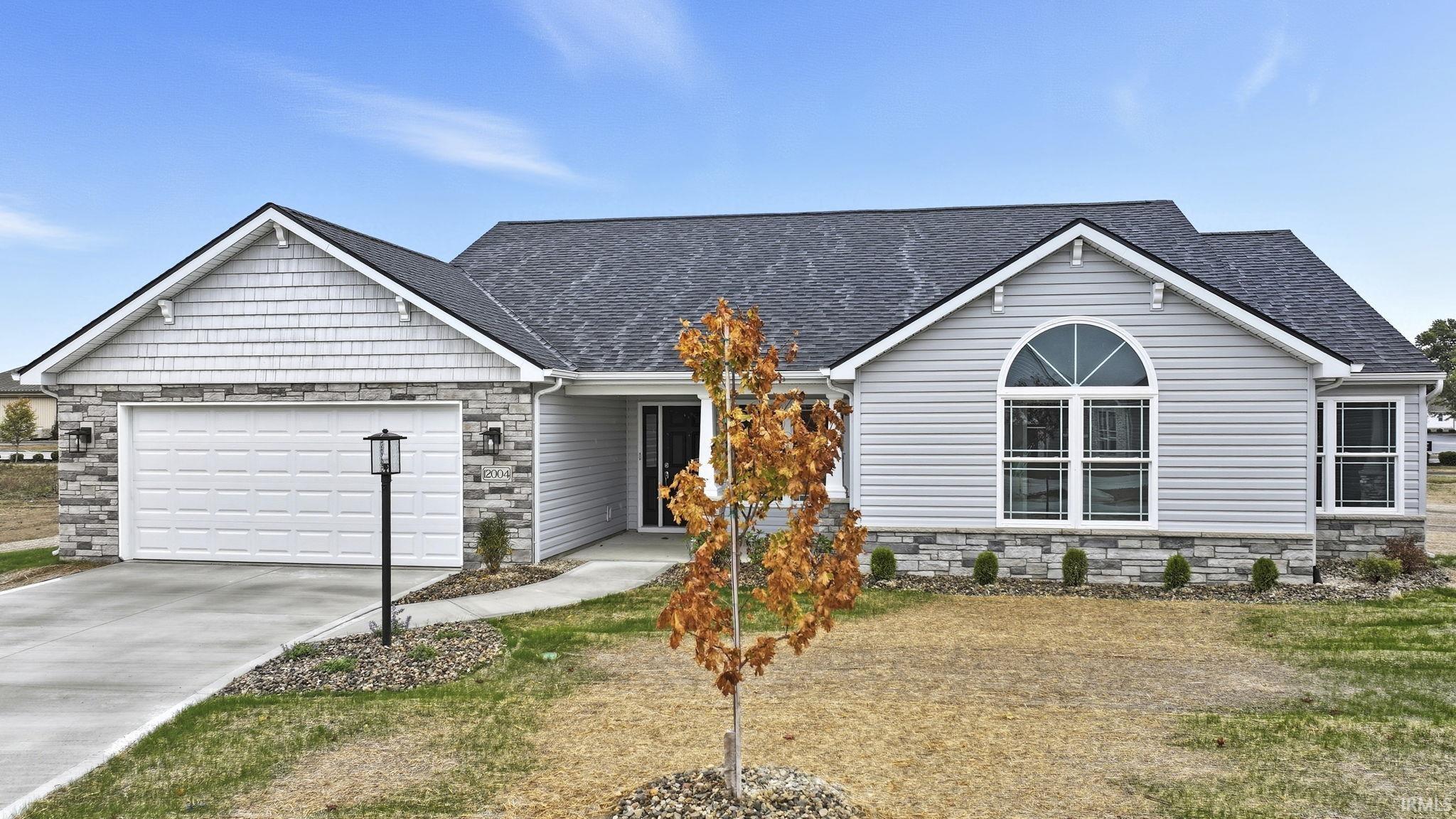 View of front facade featuring stone siding, roof with shingles, concrete driveway, and a garage
