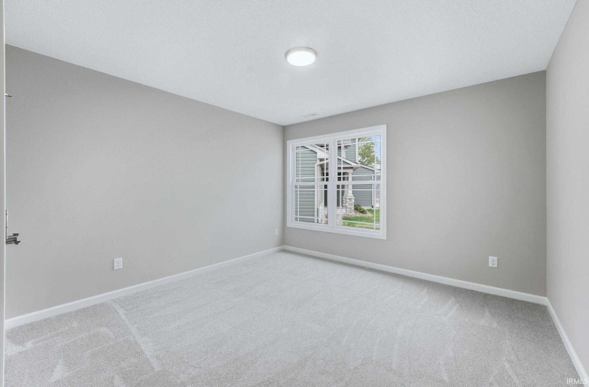 Spare room with baseboards and light colored carpet