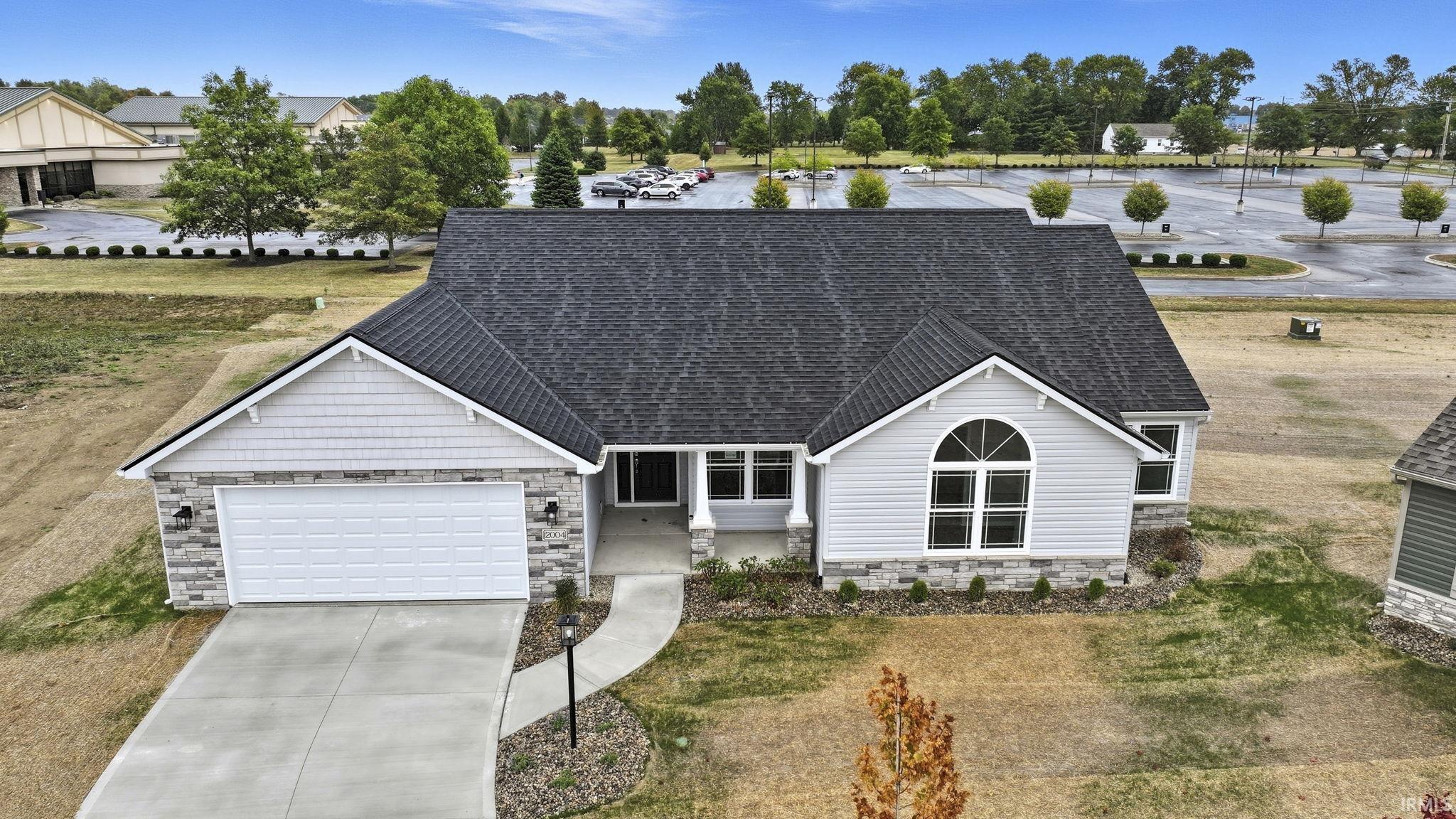 View of front of property featuring stone siding, a shingled roof, driveway, and a garage